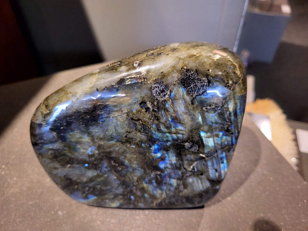 Labradoriet, 2,5kg, 14cm, hoog, 75,- euro, nr. 15
Beschrijving, Labradoriet.
Labradoriet is een edelsteen die bekend staat om zijn iriserende kleurenspel, ook wel labradoriseren genoemd, dat vaak doet denken aan het noorderlicht. Het is een populaire steen in de edelstenenwereld vanwege zowel zijn uiterlijk als zijn vermeende spirituele eigenschappen. 
Wat is labradoriet?
Labradoriet is een veldspaatmineraal dat wordt gekenmerkt door een opaalachtig glans of iriserend effect, veroorzaakt door de lichtbreking in de interne structuur van de steen.
De meest voorkomende kleur is grijs of groenachtig grijs, maar de steen kan ook blauwe, gele, oranje, paarse of zelfs rode flitsen laten zien.
De steen is genoemd naar het Canadese schiereiland Labrador, waar het voor het eerst werd ontdekt. 
Spirituele betekenis en eigenschappen:
Labradoriet wordt vaak beschouwd als een beschermende steen, vooral voor mensen die gevoelig zijn voor de energieën van hun omgeving. 
Het zou helpen bij het versterken van de aura en het verminderen van energielekkage, waardoor je je weerbaarder voelt. 
Labradoriet wordt geassocieerd met het versterken van intuïtie, het vergroten van het bewustzijn en het transformeren van negatieve energieën. 
Het wordt ook gebruikt om blokkades op te heffen en de innerlijke wijsheid te onthullen. 
Gebruik:
Labradoriet wordt vaak verwerkt in sieraden zoals hangers, armbanden en oorbellen. 
Het kan ook als ruwe steen, knuffelsteen of in andere vormen worden gebruikt, bijvoorbeeld in een huis of op een werkplek. 
Labradoriet kan worden gereinigd door het onder stromend water te houden of door het te reinigen met een andere steen zoals bergkristal of seleniet. 
Vindplaatsen:
Labradoriet wordt gevonden op verschillende locaties over de hele wereld, waaronder Canada, Finland, Madagaskar en Rusland. 
                                -Kunstgalerie Arnold-