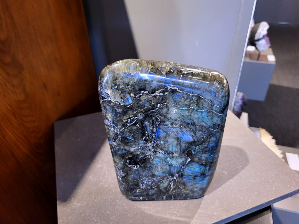 Labradoriet, 4,6kg, 22cm hoog, 137,- euro, nr. 4
Beschrijving, Labradoriet.
Labradoriet is een edelsteen die bekend staat om zijn iriserende kleurenspel, ook wel labradoriseren genoemd, dat vaak doet denken aan het noorderlicht. Het is een populaire steen in de edelstenenwereld vanwege zowel zijn uiterlijk als zijn vermeende spirituele eigenschappen. 
Wat is labradoriet?
Labradoriet is een veldspaatmineraal dat wordt gekenmerkt door een opaalachtig glans of iriserend effect, veroorzaakt door de lichtbreking in de interne structuur van de steen.
De meest voorkomende kleur is grijs of groenachtig grijs, maar de steen kan ook blauwe, gele, oranje, paarse of zelfs rode flitsen laten zien.
De steen is genoemd naar het Canadese schiereiland Labrador, waar het voor het eerst werd ontdekt. 
Spirituele betekenis en eigenschappen:
Labradoriet wordt vaak beschouwd als een beschermende steen, vooral voor mensen die gevoelig zijn voor de energieën van hun omgeving. 
Het zou helpen bij het versterken van de aura en het verminderen van energielekkage, waardoor je je weerbaarder voelt. 
Labradoriet wordt geassocieerd met het versterken van intuïtie, het vergroten van het bewustzijn en het transformeren van negatieve energieën. 
Het wordt ook gebruikt om blokkades op te heffen en de innerlijke wijsheid te onthullen. 
Gebruik:
Labradoriet wordt vaak verwerkt in sieraden zoals hangers, armbanden en oorbellen. 
Het kan ook als ruwe steen, knuffelsteen of in andere vormen worden gebruikt, bijvoorbeeld in een huis of op een werkplek. 
Labradoriet kan worden gereinigd door het onder stromend water te houden of door het te reinigen met een andere steen zoals bergkristal of seleniet. 
Vindplaatsen:
Labradoriet wordt gevonden op verschillende locaties over de hele wereld, waaronder Canada, Finland, Madagaskar en Rusland. 

                                -kunstgalerie arnold-