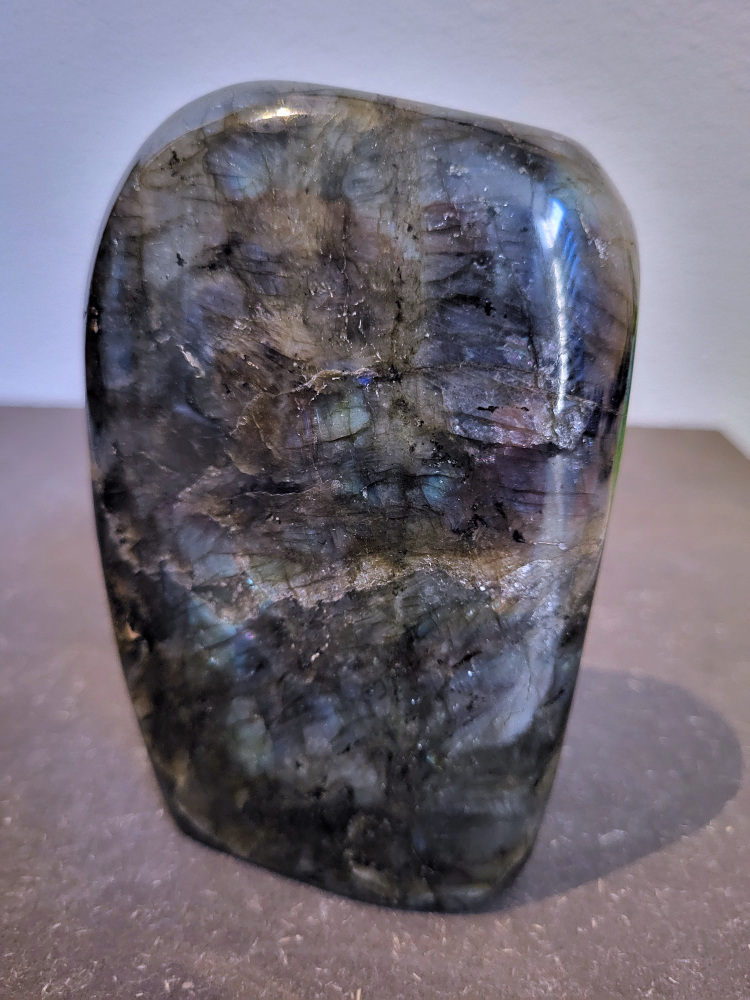 Labradoriet, 1kg, 12cm hoog, 31,- euro, nr. 53
Beschrijving, Labradoriet.
Labradoriet is een edelsteen die bekend staat om zijn iriserende kleurenspel, ook wel labradoriseren genoemd, dat vaak doet denken aan het noorderlicht. Het is een populaire steen in de edelstenenwereld vanwege zowel zijn uiterlijk als zijn vermeende spirituele eigenschappen. 
Wat is labradoriet?
Labradoriet is een veldspaatmineraal dat wordt gekenmerkt door een opaalachtig glans of iriserend effect, veroorzaakt door de lichtbreking in de interne structuur van de steen.
De meest voorkomende kleur is grijs of groenachtig grijs, maar de steen kan ook blauwe, gele, oranje, paarse of zelfs rode flitsen laten zien.
De steen is genoemd naar het Canadese schiereiland Labrador, waar het voor het eerst werd ontdekt. 
Spirituele betekenis en eigenschappen:
Labradoriet wordt vaak beschouwd als een beschermende steen, vooral voor mensen die gevoelig zijn voor de energieën van hun omgeving. 
Het zou helpen bij het versterken van de aura en het verminderen van energielekkage, waardoor je je weerbaarder voelt. 
Labradoriet wordt geassocieerd met het versterken van intuïtie, het vergroten van het bewustzijn en het transformeren van negatieve energieën. 
Het wordt ook gebruikt om blokkades op te heffen en de innerlijke wijsheid te onthullen. 
Gebruik:
Labradoriet wordt vaak verwerkt in sieraden zoals hangers, armbanden en oorbellen. 
Het kan ook als ruwe steen, knuffelsteen of in andere vormen worden gebruikt, bijvoorbeeld in een huis of op een werkplek. 
Labradoriet kan worden gereinigd door het onder stromend water te houden of door het te reinigen met een andere steen zoals bergkristal of seleniet. 
Vindplaatsen:
Labradoriet wordt gevonden op verschillende locaties over de hele wereld, waaronder Canada, Finland, Madagaskar en Rusland. 
                                -Kunstgalerie Arnold-