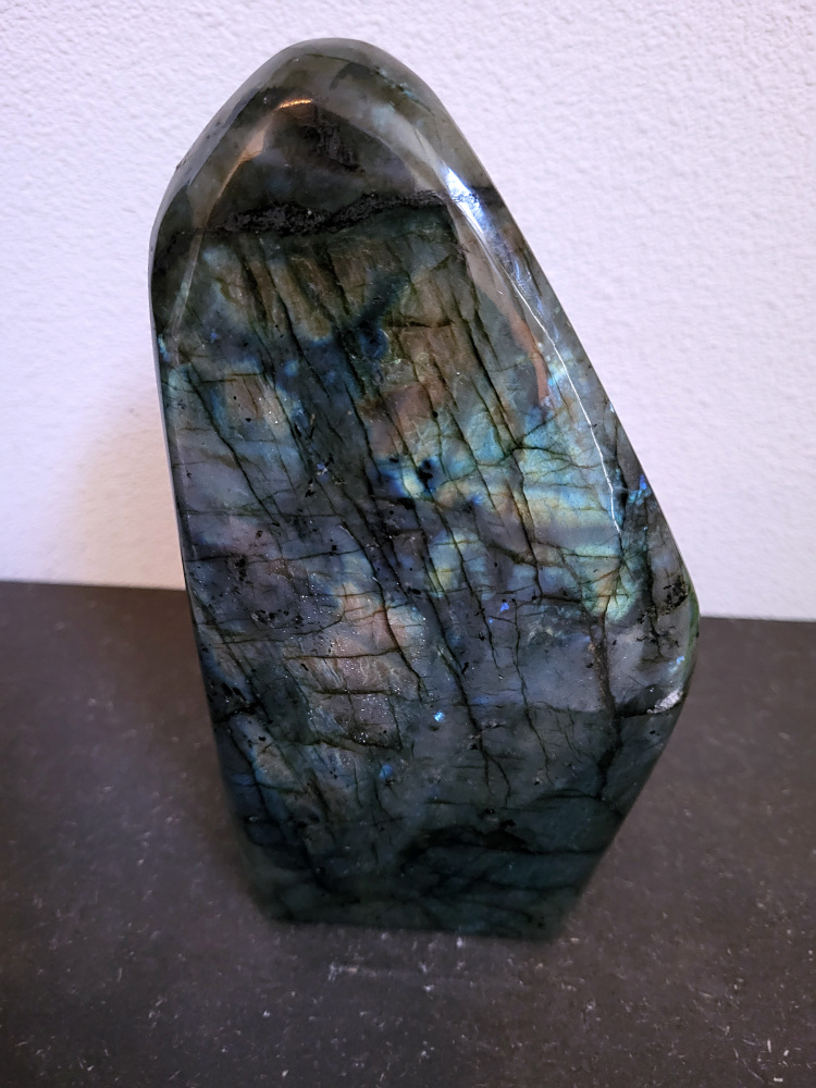 Labradoriet, 2,8kg, 20cm hoog, 85,- euro, nr. 52
Beschrijving, Labradoriet.
Labradoriet is een edelsteen die bekend staat om zijn iriserende kleurenspel, ook wel labradoriseren genoemd, dat vaak doet denken aan het noorderlicht. Het is een populaire steen in de edelstenenwereld vanwege zowel zijn uiterlijk als zijn vermeende spirituele eigenschappen. 
Wat is labradoriet?
Labradoriet is een veldspaatmineraal dat wordt gekenmerkt door een opaalachtig glans of iriserend effect, veroorzaakt door de lichtbreking in de interne structuur van de steen.
De meest voorkomende kleur is grijs of groenachtig grijs, maar de steen kan ook blauwe, gele, oranje, paarse of zelfs rode flitsen laten zien.
De steen is genoemd naar het Canadese schiereiland Labrador, waar het voor het eerst werd ontdekt. 
Spirituele betekenis en eigenschappen:
Labradoriet wordt vaak beschouwd als een beschermende steen, vooral voor mensen die gevoelig zijn voor de energieën van hun omgeving. 
Het zou helpen bij het versterken van de aura en het verminderen van energielekkage, waardoor je je weerbaarder voelt. 
Labradoriet wordt geassocieerd met het versterken van intuïtie, het vergroten van het bewustzijn en het transformeren van negatieve energieën. 
Het wordt ook gebruikt om blokkades op te heffen en de innerlijke wijsheid te onthullen. 
Gebruik:
Labradoriet wordt vaak verwerkt in sieraden zoals hangers, armbanden en oorbellen. 
Het kan ook als ruwe steen, knuffelsteen of in andere vormen worden gebruikt, bijvoorbeeld in een huis of op een werkplek. 
Labradoriet kan worden gereinigd door het onder stromend water te houden of door het te reinigen met een andere steen zoals bergkristal of seleniet. 
Vindplaatsen:
Labradoriet wordt gevonden op verschillende locaties over de hele wereld, waaronder Canada, Finland, Madagaskar en Rusland. 
                                -Kunstgalerie Arnold-