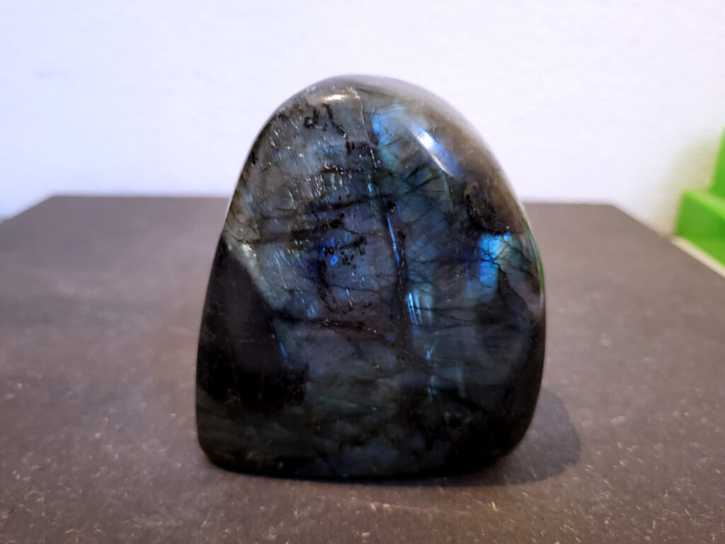 Labradoriet, 0,6 kg, 10cm hoog, 17,- euro, nr.9
Beschrijving, Labradoriet.
Labradoriet is een edelsteen die bekend staat om zijn iriserende kleurenspel, ook wel labradoriseren genoemd, dat vaak doet denken aan het noorderlicht. Het is een populaire steen in de edelstenenwereld vanwege zowel zijn uiterlijk als zijn vermeende spirituele eigenschappen. 
Wat is labradoriet?
Labradoriet is een veldspaatmineraal dat wordt gekenmerkt door een opaalachtig glans of iriserend effect, veroorzaakt door de lichtbreking in de interne structuur van de steen.
De meest voorkomende kleur is grijs of groenachtig grijs, maar de steen kan ook blauwe, gele, oranje, paarse of zelfs rode flitsen laten zien.
De steen is genoemd naar het Canadese schiereiland Labrador, waar het voor het eerst werd ontdekt. 
Spirituele betekenis en eigenschappen:
Labradoriet wordt vaak beschouwd als een beschermende steen, vooral voor mensen die gevoelig zijn voor de energieën van hun omgeving. 
Het zou helpen bij het versterken van de aura en het verminderen van energielekkage, waardoor je je weerbaarder voelt. 
Labradoriet wordt geassocieerd met het versterken van intuïtie, het vergroten van het bewustzijn en het transformeren van negatieve energieën. 
Het wordt ook gebruikt om blokkades op te heffen en de innerlijke wijsheid te onthullen. 
Gebruik:
Labradoriet wordt vaak verwerkt in sieraden zoals hangers, armbanden en oorbellen. 
Het kan ook als ruwe steen, knuffelsteen of in andere vormen worden gebruikt, bijvoorbeeld in een huis of op een werkplek. 
Labradoriet kan worden gereinigd door het onder stromend water te houden of door het te reinigen met een andere steen zoals bergkristal of seleniet. 
Vindplaatsen:
Labradoriet wordt gevonden op verschillende locaties over de hele wereld, waaronder Canada, Finland, Madagaskar en Rusland. 
                                -Kunstgalerie Arnold-