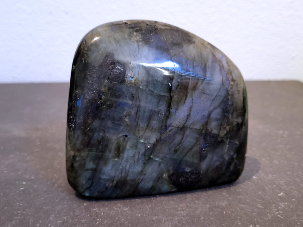 Labradoriet, 0,5kg, 9cm hoog, 16,- euro, nr. 3
Beschrijving, Labradoriet.
Labradoriet is een edelsteen die bekend staat om zijn iriserende kleurenspel, ook wel labradoriseren genoemd, dat vaak doet denken aan het noorderlicht. Het is een populaire steen in de edelstenenwereld vanwege zowel zijn uiterlijk als zijn vermeende spirituele eigenschappen. 
Wat is labradoriet?
Labradoriet is een veldspaatmineraal dat wordt gekenmerkt door een opaalachtig glans of iriserend effect, veroorzaakt door de lichtbreking in de interne structuur van de steen.
De meest voorkomende kleur is grijs of groenachtig grijs, maar de steen kan ook blauwe, gele, oranje, paarse of zelfs rode flitsen laten zien.
De steen is genoemd naar het Canadese schiereiland Labrador, waar het voor het eerst werd ontdekt. 
Spirituele betekenis en eigenschappen:
Labradoriet wordt vaak beschouwd als een beschermende steen, vooral voor mensen die gevoelig zijn voor de energieën van hun omgeving. 
Het zou helpen bij het versterken van de aura en het verminderen van energielekkage, waardoor je je weerbaarder voelt. 
Labradoriet wordt geassocieerd met het versterken van intuïtie, het vergroten van het bewustzijn en het transformeren van negatieve energieën. 
Het wordt ook gebruikt om blokkades op te heffen en de innerlijke wijsheid te onthullen. 
Gebruik:
Labradoriet wordt vaak verwerkt in sieraden zoals hangers, armbanden en oorbellen. 
Het kan ook als ruwe steen, knuffelsteen of in andere vormen worden gebruikt, bijvoorbeeld in een huis of op een werkplek. 
Labradoriet kan worden gereinigd door het onder stromend water te houden of door het te reinigen met een andere steen zoals bergkristal of seleniet. 
Vindplaatsen:
Labradoriet wordt gevonden op verschillende locaties over de hele wereld, waaronder Canada, Finland, Madagaskar en Rusland. 

                                  -kunstgalerie arnold-