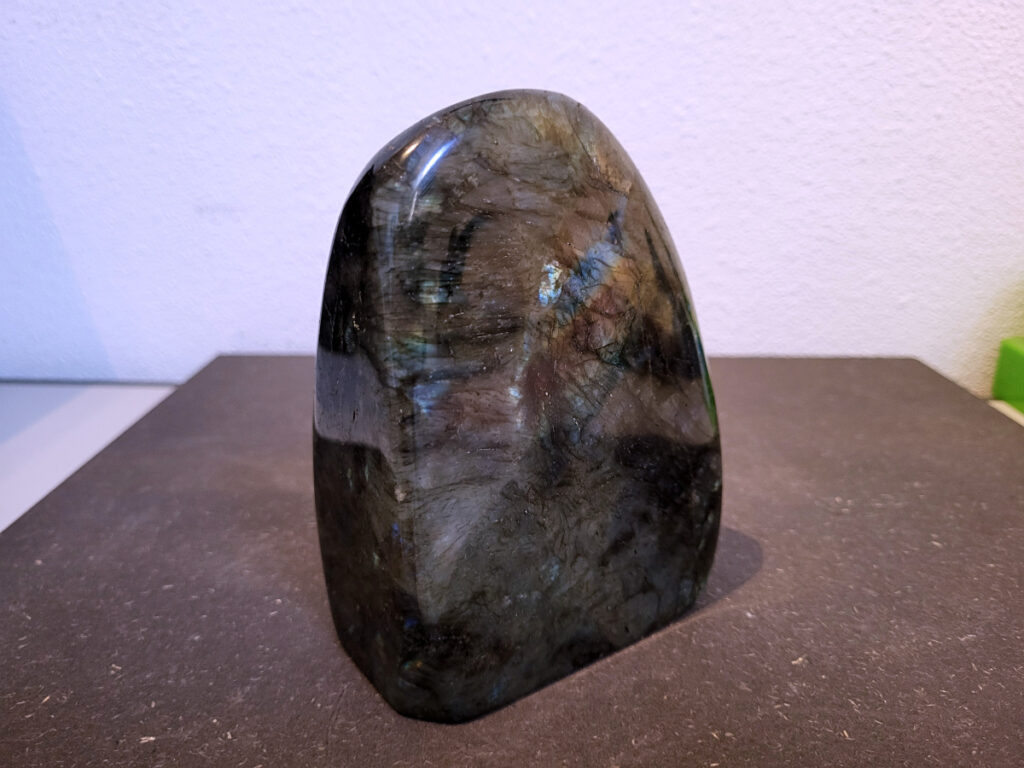 Labradoriet, 1,4kg, 13cm hoog, 41,- euro,- nr. 1
Beschrijving, Labradoriet.
Labradoriet is een edelsteen die bekend staat om zijn iriserende kleurenspel, ook wel labradoriseren genoemd, dat vaak doet denken aan het noorderlicht. Het is een populaire steen in de edelstenenwereld vanwege zowel zijn uiterlijk als zijn vermeende spirituele eigenschappen. 
Wat is labradoriet?
Labradoriet is een veldspaatmineraal dat wordt gekenmerkt door een opaalachtig glans of iriserend effect, veroorzaakt door de lichtbreking in de interne structuur van de steen.
De meest voorkomende kleur is grijs of groenachtig grijs, maar de steen kan ook blauwe, gele, oranje, paarse of zelfs rode flitsen laten zien.
De steen is genoemd naar het Canadese schiereiland Labrador, waar het voor het eerst werd ontdekt. 
Spirituele betekenis en eigenschappen:
Labradoriet wordt vaak beschouwd als een beschermende steen, vooral voor mensen die gevoelig zijn voor de energieën van hun omgeving. 
Het zou helpen bij het versterken van de aura en het verminderen van energielekkage, waardoor je je weerbaarder voelt. 
Labradoriet wordt geassocieerd met het versterken van intuïtie, het vergroten van het bewustzijn en het transformeren van negatieve energieën. 
Het wordt ook gebruikt om blokkades op te heffen en de innerlijke wijsheid te onthullen. 
Gebruik:
Labradoriet wordt vaak verwerkt in sieraden zoals hangers, armbanden en oorbellen. 
Het kan ook als ruwe steen, knuffelsteen of in andere vormen worden gebruikt, bijvoorbeeld in een huis of op een werkplek. 
Labradoriet kan worden gereinigd door het onder stromend water te houden of door het te reinigen met een andere steen zoals bergkristal of seleniet. 
Vindplaatsen:
Labradoriet wordt gevonden op verschillende locaties over de hele wereld, waaronder Canada, Finland, Madagaskar en Rusland. 

                       -kunstgalerie arnold-