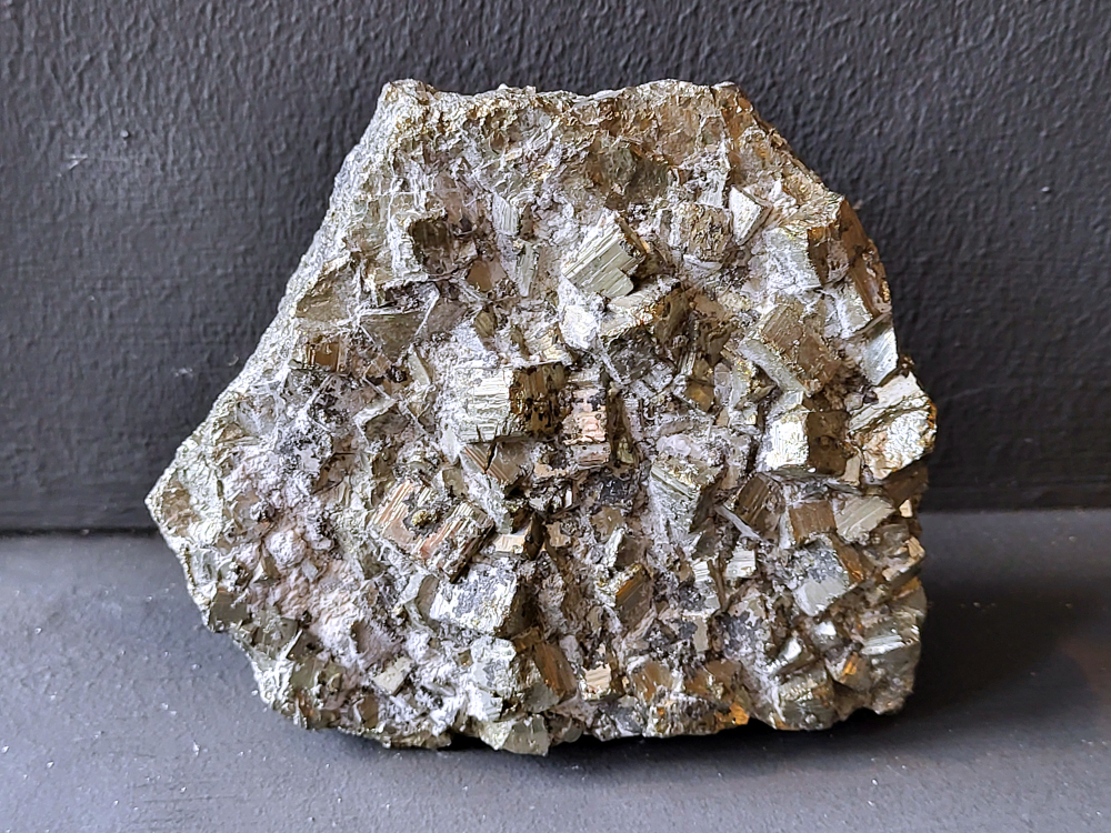 Pyriet brokstuk, 1,1 kg., 50,- euro, nr. 15

Pyriet,
Pyriet, ook wel "gekkengoud" genoemd, is een 
ijzer- en zwavelrijk mineraal met een goudgele, metaalachtige glans en vaak kubusvormige kristallen. 
De naam komt van het Griekse woord voor "vuur" ,
 omdat het vonken maakt als je erop slaat. Het is een veelvoorkomend mineraal dat in verschillende gesteentetypes wordt gevonden. 
Kenmerken: 
Uiterlijk: Goudgeel tot messing-geel met een sterke metaalglans.
Kristalstructuur: Vaak voorkomend in kubusvormige kristallen.                  
Samenstelling: Bestaat uit ijzer en zwavel,
Vormen: Verkrijgbaar als ruw materiaal, bewerkt in sieraden of in combinatie met andere stenen zoals kwarts.
Vonken: Maakt vonken bij contact met een hard oppervlak, wat de naam verklaart. 
Betekenis en gebruik 
Symboliek: Wordt geassocieerd met rijkdom, bescherming, wilskracht en creativiteit.
Spirituele toepassingen:
Versterkt assertiviteit en helpt angst te overwinnen.
Bevordert creativiteit, doorzettingsvermogen en focus.
Heeft een ondersteunende werking bij het spijsverteringsstelsel en zuurhuishouding.