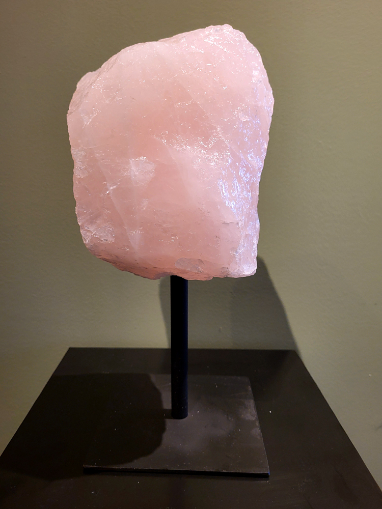 Rozenkwarts op standaard, 7,8 kg, 155,- euro, nr. 1

Rozenkwarts is een roze variëteit van kwarts, bekend om zijn zachte, liefdevolle energie en wordt vaak geassocieerd met het hartchakra. 
Kenmerken:
Rozenkwarts varieert in kleur van lichtroze tot diep roze, vaak met een doorschijnende of troebele textuur. 
Het is een mineraal dat voornamelijk bestaat uit siliciumdioxide, met sporen van titanium, ijzer of mangaan die de roze kleur veroorzaken. 
Herkomst:
Rozenkwarts wordt op veel plaatsen in de wereld gevonden, waaronder Brazilië, Madagaskar, Rusland, India en de VS, maar de kwaliteit kan variëren. 
Eigenschappen en Betekenis:

Rozenkwarts staat bekend als de "steen van de liefde" en wordt geassocieerd met het openen van het hartchakra, het bevorderen van zelfliefde, vergeving, compassie en het aantrekken van liefdevolle relaties.
Bescherming:
In sommige overtuigingen wordt rozenkwarts ook gebruikt voor bescherming en het afweren van negatieve energieën. 
Verzorging:
Rozenkwarts kan het beste niet langdurig aan direct zonlicht worden blootgesteld, omdat de kleur kan vervagen.
                           -kunstgalerie-arnold-