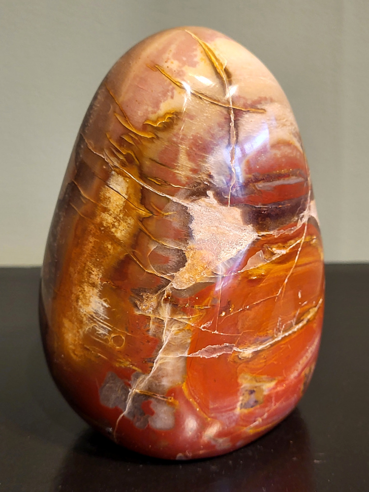 Versteend hout, 0,8 kg, 11cm hoog, 23,- euro, nr. 51
Versteend hout is miljoenen jaren oud!
Chakra: wortelchakra (Muladhara)
Waar komt versteend hout vandaan en hoe ontstaan het?
Versteend hout, of gefossiliseerd hout, ontstaat wanneer een boom na zijn overlijden bedekt wordt door sediment, waardoor het langzaam omgezet wordt in steen. In plaats van te vergaan, wordt het hout geleidelijk vervangen door mineralen zoals silica. Dit proces behoudt de originele structuur van het hout, inclusief details zoals jaarringen en nerven. Het kan miljoenen jaren duren, aangezien het water dat rijk is aan mineralen de houtcellen binnendringt, terwijl zuurstof geen rol meer speelt in de afbraak.
De kleur van versteend hout is precies zoals het hout er oorspronkelijk uit zag.
Spirituele werking van versteend hout:
> stabiliteit, rust en veiligheid
Fysiek zou het positieve effecten hebben op het skelet, de botten en de rug, en kan het ondersteuning bieden bij aandoeningen zoals osteoporose en ADHD.
- Kunstgalerie Arnold -