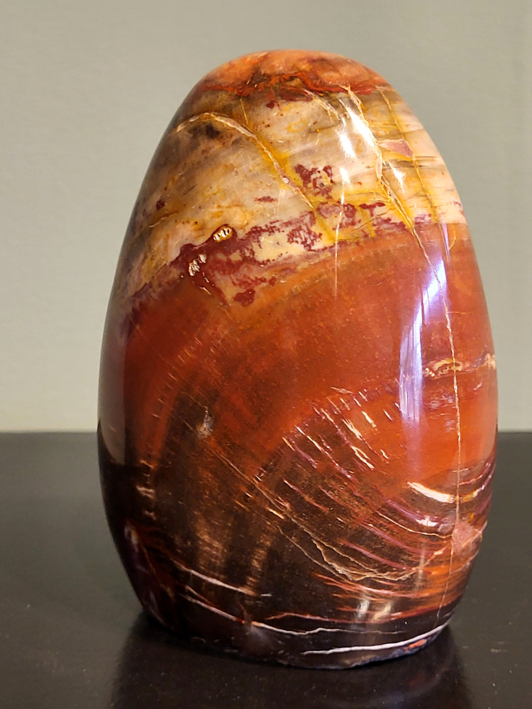 Versteend hout, 0,9 kg, 12cm hoog, 27,- euro, nr. 66
Versteend hout is miljoenen jaren oud!
Chakra: wortelchakra (Muladhara)
Waar komt versteend hout vandaan en hoe ontstaan het?
Versteend hout, of gefossiliseerd hout, ontstaat wanneer een boom na zijn overlijden bedekt wordt door sediment, waardoor het langzaam omgezet wordt in steen. In plaats van te vergaan, wordt het hout geleidelijk vervangen door mineralen zoals silica. Dit proces behoudt de originele structuur van het hout, inclusief details zoals jaarringen en nerven. Het kan miljoenen jaren duren, aangezien het water dat rijk is aan mineralen de houtcellen binnendringt, terwijl zuurstof geen rol meer speelt in de afbraak.
De kleur van versteend hout is precies zoals het hout er oorspronkelijk uit zag.
Spirituele werking van versteend hout:
> stabiliteit, rust en veiligheid
Fysiek zou het positieve effecten hebben op het skelet, de botten en de rug, en kan het ondersteuning bieden bij aandoeningen zoals osteoporose en ADHD.
- Kunstgalerie Arnold -