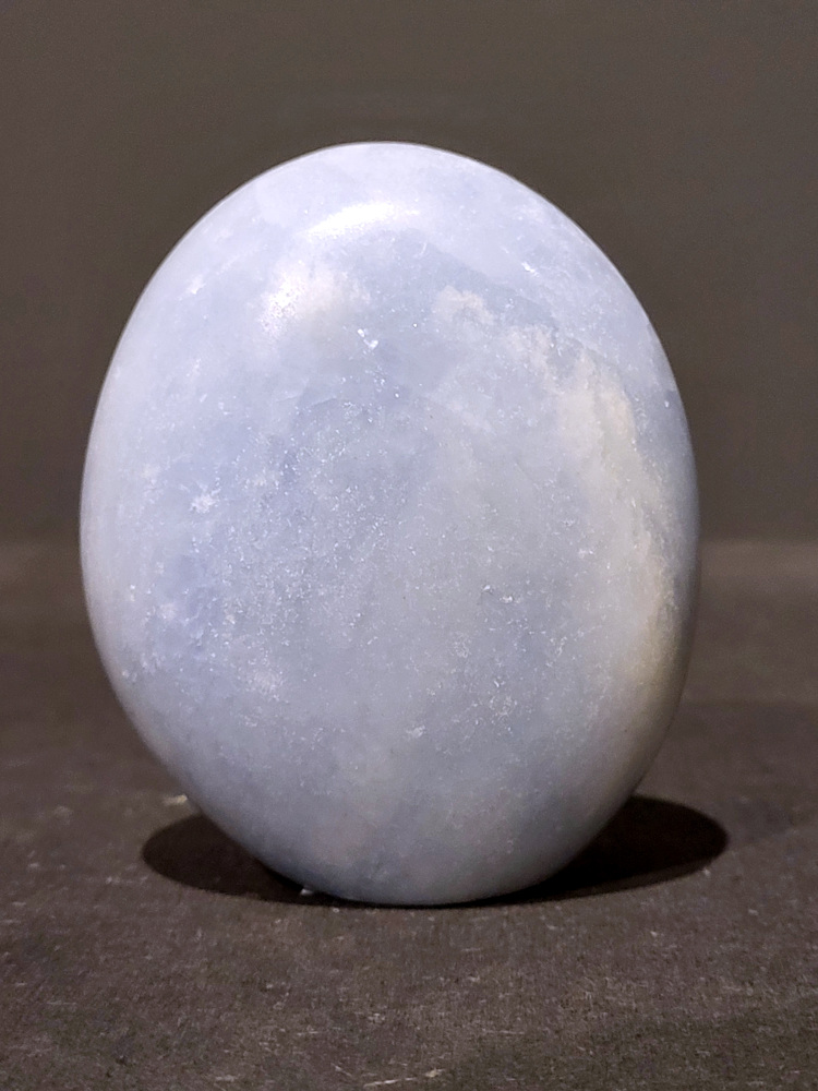 Blauwe calciet, 0,4kg, 8cm hoog, 11,-euro, nr. 11
Calciet is een veelvoorkomend mineraal dat voornamelijk bestaat uit calciumcarbonaat. Het komt in diverse kleuren en vormen voor en wordt in veel industrieën gebruikt, maar ook in de esoterie. 
Algemene kenmerken:
Samenstelling: Calciet bestaat voornamelijk uit calciumcarbonaat (CaCO3). 
Vorming: Het ontstaat door afzetting van calciumcarbonaat in water, maar ook door ophoping van schelpen en skeletten van zeedieren. 
Uiterlijk: Het heeft vaak een glasachtige glans, is doorzichtig tot doorschijnend en kan vele kleuren hebben, zoals geel, oranje, rood, bruin, blauw, groen, roze, wit en kleurloos. 
Hardheid: Calciet heeft een hardheid van 3 op de schaal van Mohs. 
Veelvoorkomend: Het is een van de meest voorkomende mineralen en is een hoofdbestanddeel van kalksteen, marmer en krijt. 
Esoterie:
In de edelsteentherapie wordt calciet gezien als een steen die energie versterkt, negatieve energieën verwijdert en spirituele groei bevordert. Verschillende kleuren calciet hebben specifieke eigenschappen, zoals gele calciet voor doorzettingsvermogen en moed, en mangano calciet voor emotionele heling. 
Specifieke calcietsoorten:
Gele Calciet: Staat bekend om het absorberen van negativiteit, het versterken van doorzettingsvermogen en het aantrekken van succes. 
Blauwe Calciet: Wordt geassocieerd met kalmering, communicatie en het loslaten van stress. 
Groene Calciet: Werkt op de hartchakra, bevordert liefde, compassie en emotionele heling. 
Mangano Calciet: Wordt gebruikt voor emotionele heling, het loslaten van oud verdriet en het versterken van zelfvertrouwen. 
Reiniging:
Calciet kan op verschillende manieren gereinigd worden, maar het is belangrijk om te weten dat sommige soorten, zoals gele calciet, niet goed tegen water kunnen. 
Andere reinigingsmethoden zijn bijvoorbeeld reinigen met edelstenenspray, op een Amethist of bergkristal leggen, of reinigen met selenite. 
Het is een steen die kan worden gebruikt voor energieversterking, emotionele heling en het bevorderen van spirituele groei, afhankelijk van de specifieke kleur en eigenschappen.