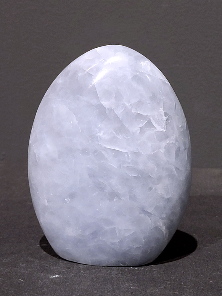 Blauwe calciet, 0,5kg, 10cm hoog, 16,- euro, nr. 1
Calciet is een veelvoorkomend mineraal dat voornamelijk bestaat uit calciumcarbonaat. Het komt in diverse kleuren en vormen voor en wordt in veel industrieën gebruikt, maar ook in de esoterie. 
Algemene kenmerken:
Samenstelling: Calciet bestaat voornamelijk uit calciumcarbonaat (CaCO3). 
Vorming: Het ontstaat door afzetting van calciumcarbonaat in water, maar ook door ophoping van schelpen en skeletten van zeedieren. 
Uiterlijk: Het heeft vaak een glasachtige glans, is doorzichtig tot doorschijnend en kan vele kleuren hebben, zoals geel, oranje, rood, bruin, blauw, groen, roze, wit en kleurloos. 
Hardheid: Calciet heeft een hardheid van 3 op de schaal van Mohs. 
Veelvoorkomend: Het is een van de meest voorkomende mineralen en is een hoofdbestanddeel van kalksteen, marmer en krijt. 
Esoterie:
In de edelsteentherapie wordt calciet gezien als een steen die energie versterkt, negatieve energieën verwijdert en spirituele groei bevordert. Verschillende kleuren calciet hebben specifieke eigenschappen, zoals gele calciet voor doorzettingsvermogen en moed, en mangano calciet voor emotionele heling. 
Specifieke calcietsoorten:
Gele Calciet: Staat bekend om het absorberen van negativiteit, het versterken van doorzettingsvermogen en het aantrekken van succes. 
Blauwe Calciet: Wordt geassocieerd met kalmering, communicatie en het loslaten van stress. 
Groene Calciet: Werkt op de hartchakra, bevordert liefde, compassie en emotionele heling. 
Mangano Calciet: Wordt gebruikt voor emotionele heling, het loslaten van oud verdriet en het versterken van zelfvertrouwen. 
Reiniging:
Calciet kan op verschillende manieren gereinigd worden, maar het is belangrijk om te weten dat sommige soorten, zoals gele calciet, niet goed tegen water kunnen. 
Andere reinigingsmethoden zijn bijvoorbeeld reinigen met edelstenenspray, op een Amethist of bergkristal leggen, of reinigen met selenite. 
Het is een steen die kan worden gebruikt voor energieversterking, emotionele heling en het bevorderen van spirituele groei, afhankelijk van de specifieke kleur en eigenschappen. 
                                                    -Kunstgalerie Arnold-