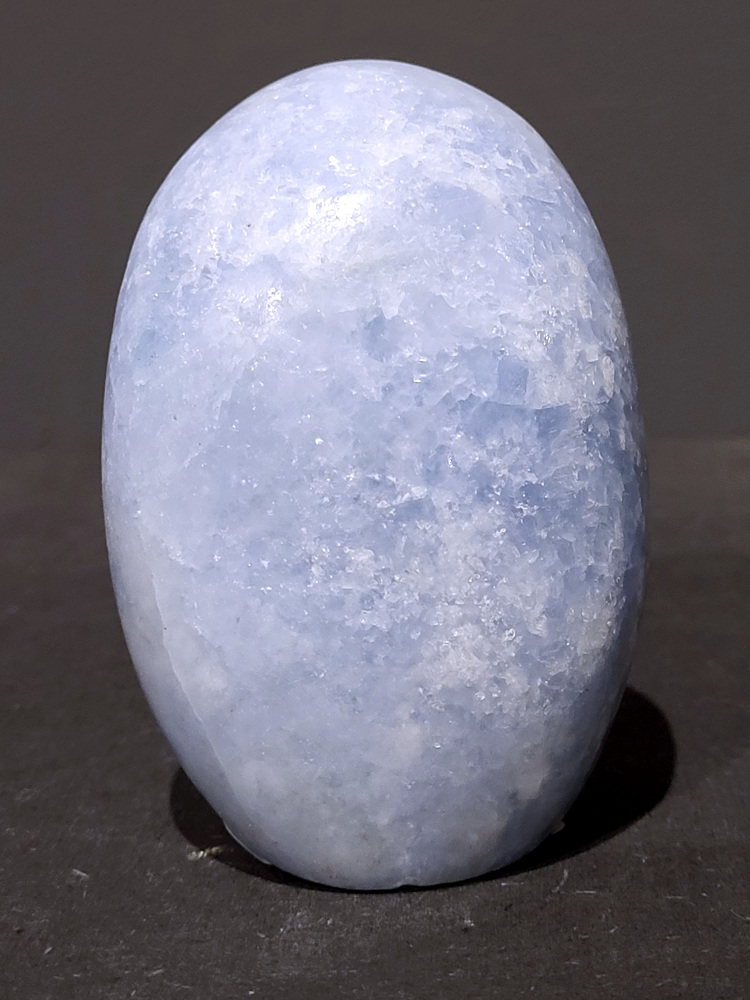 Blauwe calciet, 0,5kg, 9cm hoog, 15,- euro, nr. 14
Calciet is een veelvoorkomend mineraal dat voornamelijk bestaat uit calciumcarbonaat. Het komt in diverse kleuren en vormen voor en wordt in veel industrieën gebruikt, maar ook in de esoterie. 
Algemene kenmerken:
Samenstelling: Calciet bestaat voornamelijk uit calciumcarbonaat (CaCO3). 
Vorming: Het ontstaat door afzetting van calciumcarbonaat in water, maar ook door ophoping van schelpen en skeletten van zeedieren. 
Uiterlijk: Het heeft vaak een glasachtige glans, is doorzichtig tot doorschijnend en kan vele kleuren hebben, zoals geel, oranje, rood, bruin, blauw, groen, roze, wit en kleurloos. 
Hardheid: Calciet heeft een hardheid van 3 op de schaal van Mohs. 
Veelvoorkomend: Het is een van de meest voorkomende mineralen en is een hoofdbestanddeel van kalksteen, marmer en krijt. 
Esoterie:
In de edelsteentherapie wordt calciet gezien als een steen die energie versterkt, negatieve energieën verwijdert en spirituele groei bevordert. Verschillende kleuren calciet hebben specifieke eigenschappen, zoals gele calciet voor doorzettingsvermogen en moed, en mangano calciet voor emotionele heling. 
Specifieke calcietsoorten:
Gele Calciet: Staat bekend om het absorberen van negativiteit, het versterken van doorzettingsvermogen en het aantrekken van succes. 
Blauwe Calciet: Wordt geassocieerd met kalmering, communicatie en het loslaten van stress. 
Groene Calciet: Werkt op de hartchakra, bevordert liefde, compassie en emotionele heling. 
Mangano Calciet: Wordt gebruikt voor emotionele heling, het loslaten van oud verdriet en het versterken van zelfvertrouwen. 
Reiniging:
Calciet kan op verschillende manieren gereinigd worden, maar het is belangrijk om te weten dat sommige soorten, zoals gele calciet, niet goed tegen water kunnen. 
Andere reinigingsmethoden zijn bijvoorbeeld reinigen met edelstenenspray, op een Amethist of bergkristal leggen, of reinigen met selenite. 
Het is een steen die kan worden gebruikt voor energieversterking, emotionele heling en het bevorderen van spirituele groei, afhankelijk van de specifieke kleur en eigenschappen.