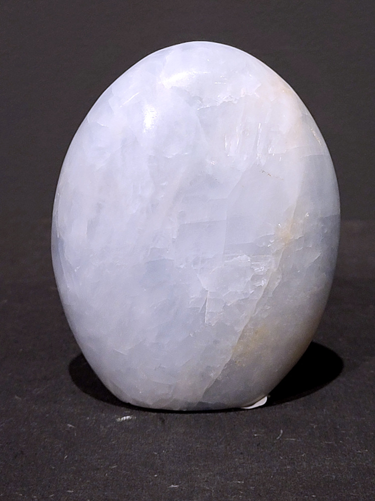 Blauwe calciet, 0,6kg, 11cm hoog, 18,- euro, nr. 16
Calciet is een veelvoorkomend mineraal dat voornamelijk bestaat uit calciumcarbonaat. Het komt in diverse kleuren en vormen voor en wordt in veel industrieën gebruikt, maar ook in de esoterie. 
Algemene kenmerken:
Samenstelling: Calciet bestaat voornamelijk uit calciumcarbonaat (CaCO3). 
Vorming: Het ontstaat door afzetting van calciumcarbonaat in water, maar ook door ophoping van schelpen en skeletten van zeedieren. 
Uiterlijk: Het heeft vaak een glasachtige glans, is doorzichtig tot doorschijnend en kan vele kleuren hebben, zoals geel, oranje, rood, bruin, blauw, groen, roze, wit en kleurloos. 
Hardheid: Calciet heeft een hardheid van 3 op de schaal van Mohs. 
Veelvoorkomend: Het is een van de meest voorkomende mineralen en is een hoofdbestanddeel van kalksteen, marmer en krijt. 
Esoterie:
In de edelsteentherapie wordt calciet gezien als een steen die energie versterkt, negatieve energieën verwijdert en spirituele groei bevordert. Verschillende kleuren calciet hebben specifieke eigenschappen, zoals gele calciet voor doorzettingsvermogen en moed, en mangano calciet voor emotionele heling. 
Specifieke calcietsoorten:
Gele Calciet: Staat bekend om het absorberen van negativiteit, het versterken van doorzettingsvermogen en het aantrekken van succes. 
Blauwe Calciet: Wordt geassocieerd met kalmering, communicatie en het loslaten van stress. 
Groene Calciet: Werkt op de hartchakra, bevordert liefde, compassie en emotionele heling. 
Mangano Calciet: Wordt gebruikt voor emotionele heling, het loslaten van oud verdriet en het versterken van zelfvertrouwen. 
Reiniging:
Calciet kan op verschillende manieren gereinigd worden, maar het is belangrijk om te weten dat sommige soorten, zoals gele calciet, niet goed tegen water kunnen. 
Andere reinigingsmethoden zijn bijvoorbeeld reinigen met edelstenenspray, op een Amethist of bergkristal leggen, of reinigen met selenite. 
Het is een steen die kan worden gebruikt voor energieversterking, emotionele heling en het bevorderen van spirituele groei, afhankelijk van de specifieke kleur en eigenschappen. 
                                                    -Kunstgalerie Arnold-