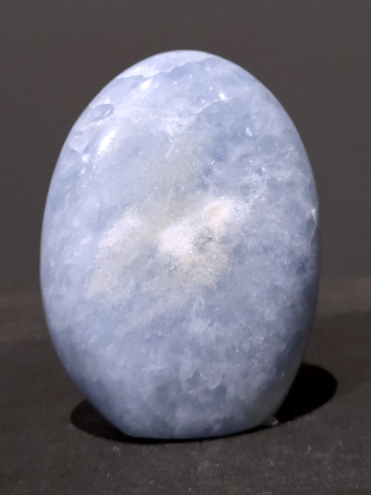 Blauwe calciet, 0,8kg, 12cm hoog, 23,- euro, nr. 22
Calciet is een veelvoorkomend mineraal dat voornamelijk bestaat uit calciumcarbonaat. Het komt in diverse kleuren en vormen voor en wordt in veel industrieën gebruikt, maar ook in de esoterie. 
Algemene kenmerken:
Samenstelling: Calciet bestaat voornamelijk uit calciumcarbonaat (CaCO3). 
Vorming: Het ontstaat door afzetting van calciumcarbonaat in water, maar ook door ophoping van schelpen en skeletten van zeedieren. 
Uiterlijk: Het heeft vaak een glasachtige glans, is doorzichtig tot doorschijnend en kan vele kleuren hebben, zoals geel, oranje, rood, bruin, blauw, groen, roze, wit en kleurloos. 
Hardheid: Calciet heeft een hardheid van 3 op de schaal van Mohs. 
Veelvoorkomend: Het is een van de meest voorkomende mineralen en is een hoofdbestanddeel van kalksteen, marmer en krijt. 
Esoterie:
In de edelsteentherapie wordt calciet gezien als een steen die energie versterkt, negatieve energieën verwijdert en spirituele groei bevordert. Verschillende kleuren calciet hebben specifieke eigenschappen, zoals gele calciet voor doorzettingsvermogen en moed, en mangano calciet voor emotionele heling. 
Specifieke calcietsoorten:
Gele Calciet: Staat bekend om het absorberen van negativiteit, het versterken van doorzettingsvermogen en het aantrekken van succes. 
Blauwe Calciet: Wordt geassocieerd met kalmering, communicatie en het loslaten van stress. 
Groene Calciet: Werkt op de hartchakra, bevordert liefde, compassie en emotionele heling. 
Mangano Calciet: Wordt gebruikt voor emotionele heling, het loslaten van oud verdriet en het versterken van zelfvertrouwen. 
Reiniging:
Calciet kan op verschillende manieren gereinigd worden, maar het is belangrijk om te weten dat sommige soorten, zoals gele calciet, niet goed tegen water kunnen. 
Andere reinigingsmethoden zijn bijvoorbeeld reinigen met edelstenenspray, op een Amethist of bergkristal leggen, of reinigen met selenite. 
Het is een steen die kan worden gebruikt voor energieversterking, emotionele heling en het bevorderen van spirituele groei, afhankelijk van de specifieke kleur en eigenschappen. 
                                                    -Kunstgalerie Arnold-