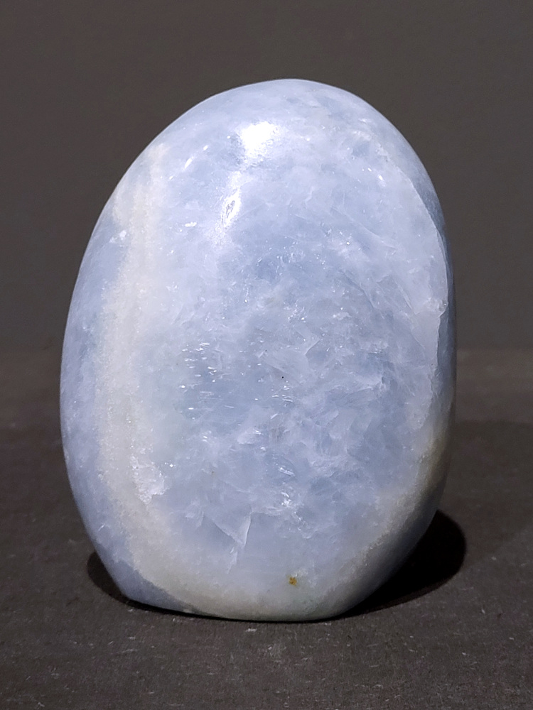 Blauwe calciet, sculptuur, 0,9kg, 11cm hoog, 26,- euro, nr. 44
Calciet is een veelvoorkomend mineraal dat voornamelijk bestaat uit calciumcarbonaat. Het komt in diverse kleuren en vormen voor en wordt in veel industrieën gebruikt, maar ook in de esoterie. 
Algemene kenmerken:
Samenstelling: Calciet bestaat voornamelijk uit calciumcarbonaat (CaCO3). 
Vorming: Het ontstaat door afzetting van calciumcarbonaat in water, maar ook door ophoping van schelpen en skeletten van zeedieren. 
Uiterlijk: Het heeft vaak een glasachtige glans, is doorzichtig tot doorschijnend en kan vele kleuren hebben, zoals geel, oranje, rood, bruin, blauw, groen, roze, wit en kleurloos. 
Hardheid: Calciet heeft een hardheid van 3 op de schaal van Mohs. 
Veelvoorkomend: Het is een van de meest voorkomende mineralen en is een hoofdbestanddeel van kalksteen, marmer en krijt. 
Esoterie:
In de edelsteentherapie wordt calciet gezien als een steen die energie versterkt, negatieve energieën verwijdert en spirituele groei bevordert. Verschillende kleuren calciet hebben specifieke eigenschappen, zoals gele calciet voor doorzettingsvermogen en moed, en mangano calciet voor emotionele heling. 
Specifieke calcietsoorten:
Gele Calciet: Staat bekend om het absorberen van negativiteit, het versterken van doorzettingsvermogen en het aantrekken van succes. 
Blauwe Calciet: Wordt geassocieerd met kalmering, communicatie en het loslaten van stress. 
Groene Calciet: Werkt op de hartchakra, bevordert liefde, compassie en emotionele heling. 
Mangano Calciet: Wordt gebruikt voor emotionele heling, het loslaten van oud verdriet en het versterken van zelfvertrouwen. 
Reiniging:
Calciet kan op verschillende manieren gereinigd worden, maar het is belangrijk om te weten dat sommige soorten, zoals gele calciet, niet goed tegen water kunnen. 
Andere reinigingsmethoden zijn bijvoorbeeld reinigen met edelstenenspray, op een Amethist of bergkristal leggen, of reinigen met selenite. 
Het is een steen die kan worden gebruikt voor energieversterking, emotionele heling en het bevorderen van spirituele groei, afhankelijk van de specifieke kleur en eigenschappen. 
                                                    -Kunstgalerie Arnold-