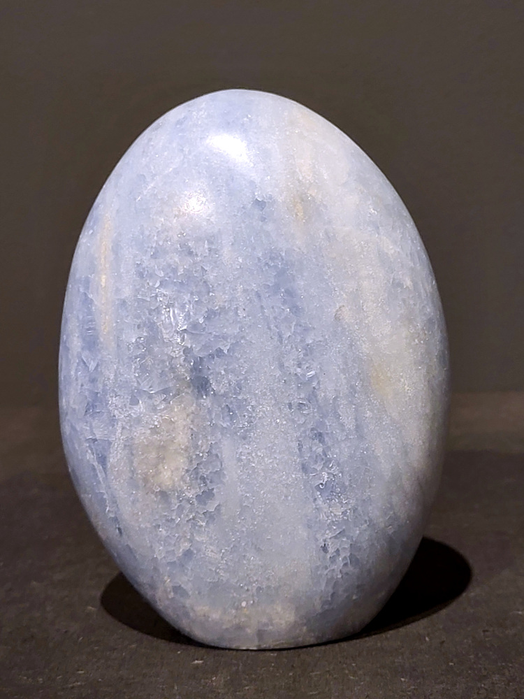 Blauwe calciet, sculptuur, 1kg, 12cm hoog, 30,- euro, nr. 45
Calciet is een veelvoorkomend mineraal dat voornamelijk bestaat uit calciumcarbonaat. Het komt in diverse kleuren en vormen voor en wordt in veel industrieën gebruikt, maar ook in de esoterie. 
Algemene kenmerken:
Samenstelling: Calciet bestaat voornamelijk uit calciumcarbonaat (CaCO3). 
Vorming: Het ontstaat door afzetting van calciumcarbonaat in water, maar ook door ophoping van schelpen en skeletten van zeedieren. 
Uiterlijk: Het heeft vaak een glasachtige glans, is doorzichtig tot doorschijnend en kan vele kleuren hebben, zoals geel, oranje, rood, bruin, blauw, groen, roze, wit en kleurloos. 
Hardheid: Calciet heeft een hardheid van 3 op de schaal van Mohs. 
Veelvoorkomend: Het is een van de meest voorkomende mineralen en is een hoofdbestanddeel van kalksteen, marmer en krijt. 
Esoterie:
In de edelsteentherapie wordt calciet gezien als een steen die energie versterkt, negatieve energieën verwijdert en spirituele groei bevordert. Verschillende kleuren calciet hebben specifieke eigenschappen, zoals gele calciet voor doorzettingsvermogen en moed, en mangano calciet voor emotionele heling. 
Specifieke calcietsoorten:
Gele Calciet: Staat bekend om het absorberen van negativiteit, het versterken van doorzettingsvermogen en het aantrekken van succes. 
Blauwe Calciet: Wordt geassocieerd met kalmering, communicatie en het loslaten van stress. 
Groene Calciet: Werkt op de hartchakra, bevordert liefde, compassie en emotionele heling. 
Mangano Calciet: Wordt gebruikt voor emotionele heling, het loslaten van oud verdriet en het versterken van zelfvertrouwen. 
Reiniging:
Calciet kan op verschillende manieren gereinigd worden, maar het is belangrijk om te weten dat sommige soorten, zoals gele calciet, niet goed tegen water kunnen. 
Andere reinigingsmethoden zijn bijvoorbeeld reinigen met edelstenenspray, op een Amethist of bergkristal leggen, of reinigen met selenite. 
Het is een steen die kan worden gebruikt voor energieversterking, emotionele heling en het bevorderen van spirituele groei, afhankelijk van de specifieke kleur en eigenschappen. 
                                                    -Kunstgalerie Arnold-