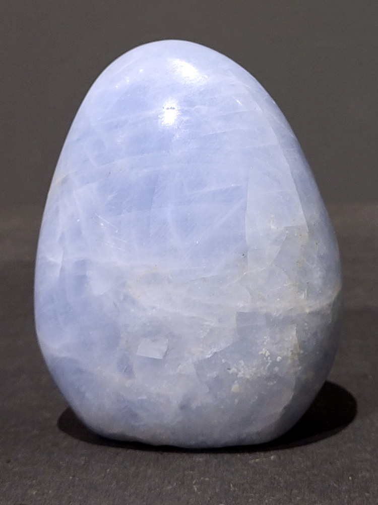 Blauwe calciet, 0,6kg, 11cm hoog, 18,-euro, nr. 46
Calciet is een veelvoorkomend mineraal dat voornamelijk bestaat uit calciumcarbonaat. Het komt in diverse kleuren en vormen voor en wordt in veel industrieën gebruikt, maar ook in de esoterie. 
Algemene kenmerken:
Samenstelling: Calciet bestaat voornamelijk uit calciumcarbonaat (CaCO3). 
Vorming: Het ontstaat door afzetting van calciumcarbonaat in water, maar ook door ophoping van schelpen en skeletten van zeedieren. 
Uiterlijk: Het heeft vaak een glasachtige glans, is doorzichtig tot doorschijnend en kan vele kleuren hebben, zoals geel, oranje, rood, bruin, blauw, groen, roze, wit en kleurloos. 
Hardheid: Calciet heeft een hardheid van 3 op de schaal van Mohs. 
Veelvoorkomend: Het is een van de meest voorkomende mineralen en is een hoofdbestanddeel van kalksteen, marmer en krijt. 
Esoterie:
In de edelsteentherapie wordt calciet gezien als een steen die energie versterkt, negatieve energieën verwijdert en spirituele groei bevordert. Verschillende kleuren calciet hebben specifieke eigenschappen, zoals gele calciet voor doorzettingsvermogen en moed, en mangano calciet voor emotionele heling. 
Specifieke calcietsoorten:
Gele Calciet: Staat bekend om het absorberen van negativiteit, het versterken van doorzettingsvermogen en het aantrekken van succes. 
Blauwe Calciet: Wordt geassocieerd met kalmering, communicatie en het loslaten van stress. 
Groene Calciet: Werkt op de hartchakra, bevordert liefde, compassie en emotionele heling. 
Mangano Calciet: Wordt gebruikt voor emotionele heling, het loslaten van oud verdriet en het versterken van zelfvertrouwen. 
Reiniging:
Calciet kan op verschillende manieren gereinigd worden, maar het is belangrijk om te weten dat sommige soorten, zoals gele calciet, niet goed tegen water kunnen. 
Andere reinigingsmethoden zijn bijvoorbeeld reinigen met edelstenenspray, op een Amethist of bergkristal leggen, of reinigen met selenite. 
Het is een steen die kan worden gebruikt voor energieversterking, emotionele heling en het bevorderen van spirituele groei, afhankelijk van de specifieke kleur en eigenschappen. 
                                                    -Kunstgalerie Arnold-