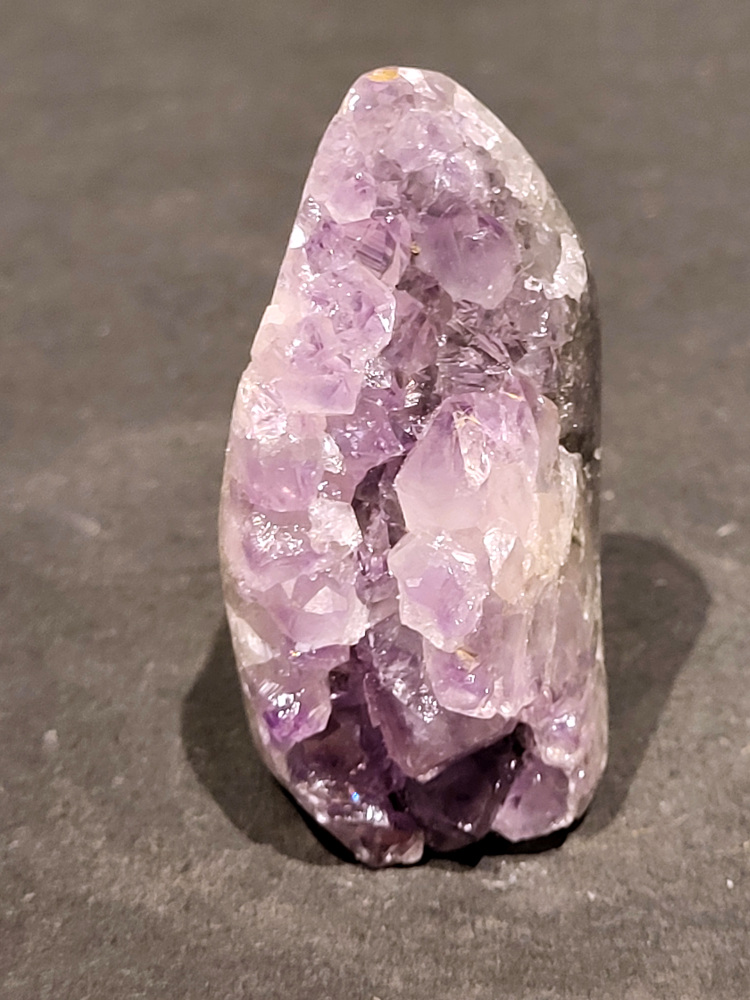 Amethist druzy, 0,1kg, 5,- euro, nr. 2.

Beschrijving Amethist.
Amethist is een paarse variëteit van kwarts, bekend om zijn kalmerende en spirituele eigenschappen. De kleur varieert van licht lila tot diep violet en wordt veroorzaakt door sporen van ijzer en andere elementen. Amethist wordt al eeuwenlang gewaardeerd, zowel vanwege zijn esthetische schoonheid als zijn vermeende genezende en beschermende krachten. 
Amethist is een kwartskristal, vaak te vinden in geodes (holtes in gesteente) of als afzonderlijke kristallen. 
De kleur varieert van lichtpaars tot diep violet, soms met roze of blauwe tinten. 
De kleurintensiteit kan variëren, waarbij donkerdere amethisten vaak als kwalitatief worden beschouwd. 
Soms vertoont amethist dichroïsme, waarbij je verschillende kleuren kunt zien wanneer je de steen in het licht draait. 

Vindplaatsen:
Amethist wordt gevonden in verschillende delen van de wereld, waaronder Brazilië, Uruguay, Zambia, Madagaskar, Rusland en Canada.
Het wordt vaak gevonden in bergachtige gebieden. 

Gebruik:
Amethist wordt gebruikt in sieraden, decoratieve objecten en als helende steen. 
Het wordt vaak gedragen als hanger, ring of armband, of geplaatst in ruimtes om de energie te zuiveren. 
Amethist wordt ook gebruikt in meditatie en andere spirituele praktijken. 