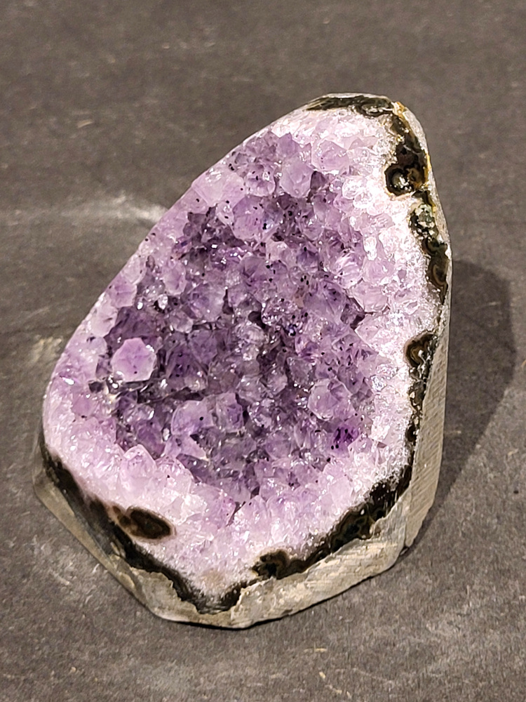 Amethist druzy, 0,2kg, 10,- euro, nr.9

Beschrijving Amethist.
Amethist is een paarse variëteit van kwarts, bekend om zijn kalmerende en spirituele eigenschappen. De kleur varieert van licht lila tot diep violet en wordt veroorzaakt door sporen van ijzer en andere elementen. Amethist wordt al eeuwenlang gewaardeerd, zowel vanwege zijn esthetische schoonheid als zijn vermeende genezende en beschermende krachten. 
Amethist is een kwartskristal, vaak te vinden in geodes (holtes in gesteente) of als afzonderlijke kristallen. 
De kleur varieert van lichtpaars tot diep violet, soms met roze of blauwe tinten. 
De kleurintensiteit kan variëren, waarbij donkerdere amethisten vaak als kwalitatief worden beschouwd. 
Soms vertoont amethist dichroïsme, waarbij je verschillende kleuren kunt zien wanneer je de steen in het licht draait. 

Vindplaatsen:
Amethist wordt gevonden in verschillende delen van de wereld, waaronder Brazilië, Uruguay, Zambia, Madagaskar, Rusland en Canada.
Het wordt vaak gevonden in bergachtige gebieden. 

Gebruik:
Amethist wordt gebruikt in sieraden, decoratieve objecten en als helende steen. 
Het wordt vaak gedragen als hanger, ring of armband, of geplaatst in ruimtes om de energie te zuiveren. 
Amethist wordt ook gebruikt in meditatie en andere spirituele praktijken. 