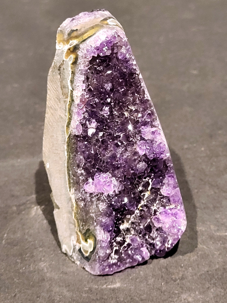 Amethist druzy, 0,3 kg, 10,- euro, nr. 8

Beschrijving Amethist.
Amethist is een paarse variëteit van kwarts, bekend om zijn kalmerende en spirituele eigenschappen. De kleur varieert van licht lila tot diep violet en wordt veroorzaakt door sporen van ijzer en andere elementen. Amethist wordt al eeuwenlang gewaardeerd, zowel vanwege zijn esthetische schoonheid als zijn vermeende genezende en beschermende krachten. 
Amethist is een kwartskristal, vaak te vinden in geodes (holtes in gesteente) of als afzonderlijke kristallen. 
De kleur varieert van lichtpaars tot diep violet, soms met roze of blauwe tinten. 
De kleurintensiteit kan variëren, waarbij donkerdere amethisten vaak als kwalitatief worden beschouwd. 
Soms vertoont amethist dichroïsme, waarbij je verschillende kleuren kunt zien wanneer je de steen in het licht draait. 

Vindplaatsen:
Amethist wordt gevonden in verschillende delen van de wereld, waaronder Brazilië, Uruguay, Zambia, Madagaskar, Rusland en Canada.
Het wordt vaak gevonden in bergachtige gebieden. 

Gebruik:
Amethist wordt gebruikt in sieraden, decoratieve objecten en als helende steen. 
Het wordt vaak gedragen als hanger, ring of armband, of geplaatst in ruimtes om de energie te zuiveren. 
Amethist wordt ook gebruikt in meditatie en andere spirituele praktijken. 