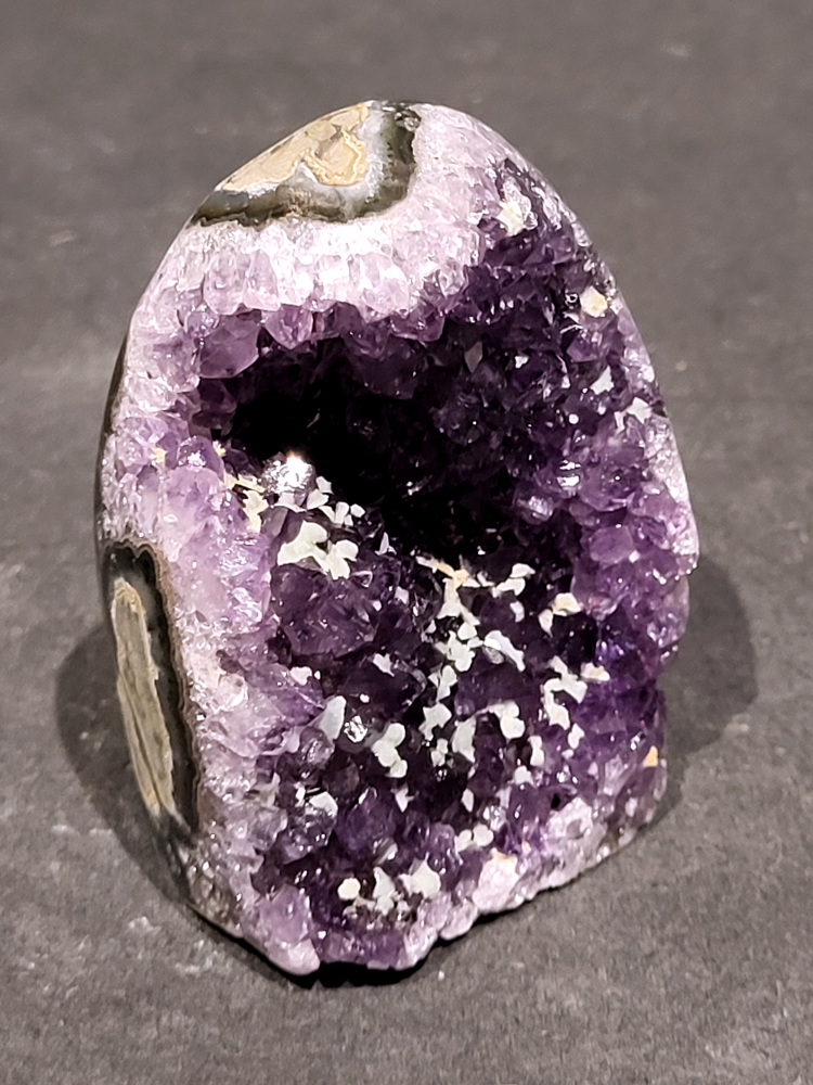 Amethist druzy, 0,2kg, 6,- euro, nr. 3.

Beschrijving Amethist.
Amethist is een paarse variëteit van kwarts, bekend om zijn kalmerende en spirituele eigenschappen. De kleur varieert van licht lila tot diep violet en wordt veroorzaakt door sporen van ijzer en andere elementen. Amethist wordt al eeuwenlang gewaardeerd, zowel vanwege zijn esthetische schoonheid als zijn vermeende genezende en beschermende krachten. 
Amethist is een kwartskristal, vaak te vinden in geodes (holtes in gesteente) of als afzonderlijke kristallen. 
De kleur varieert van lichtpaars tot diep violet, soms met roze of blauwe tinten. 
De kleurintensiteit kan variëren, waarbij donkerdere amethisten vaak als kwalitatief worden beschouwd. 
Soms vertoont amethist dichroïsme, waarbij je verschillende kleuren kunt zien wanneer je de steen in het licht draait. 

Vindplaatsen:
Amethist wordt gevonden in verschillende delen van de wereld, waaronder Brazilië, Uruguay, Zambia, Madagaskar, Rusland en Canada.
Het wordt vaak gevonden in bergachtige gebieden. 

Gebruik:
Amethist wordt gebruikt in sieraden, decoratieve objecten en als helende steen. 
Het wordt vaak gedragen als hanger, ring of armband, of geplaatst in ruimtes om de energie te zuiveren. 
Amethist wordt ook gebruikt in meditatie en andere spirituele praktijken. 