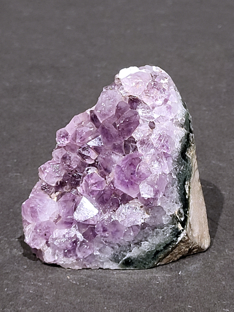 Amethist druzy, 0,3kg, 12,- euro, nr.21

Beschrijving Amethist.
Amethist is een paarse variëteit van kwarts, bekend om zijn kalmerende en spirituele eigenschappen. De kleur varieert van licht lila tot diep violet en wordt veroorzaakt door sporen van ijzer en andere elementen. Amethist wordt al eeuwenlang gewaardeerd, zowel vanwege zijn esthetische schoonheid als zijn vermeende genezende en beschermende krachten. 
Amethist is een kwartskristal, vaak te vinden in geodes (holtes in gesteente) of als afzonderlijke kristallen. 
De kleur varieert van lichtpaars tot diep violet, soms met roze of blauwe tinten. 
De kleurintensiteit kan variëren, waarbij donkerdere amethisten vaak als kwalitatief worden beschouwd. 
Soms vertoont amethist dichroïsme, waarbij je verschillende kleuren kunt zien wanneer je de steen in het licht draait. 

Vindplaatsen:
Amethist wordt gevonden in verschillende delen van de wereld, waaronder Brazilië, Uruguay, Zambia, Madagaskar, Rusland en Canada.
Het wordt vaak gevonden in bergachtige gebieden. 

Gebruik:
Amethist wordt gebruikt in sieraden, decoratieve objecten en als helende steen. 
Het wordt vaak gedragen als hanger, ring of armband, of geplaatst in ruimtes om de energie te zuiveren. 
Amethist wordt ook gebruikt in meditatie en andere spirituele praktijken. 