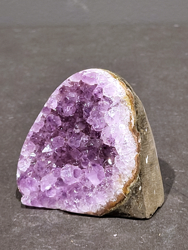 Amethist druzy, 0,3kg, 12,- euro, nr. 20

Beschrijving Amethist.
Amethist is een paarse variëteit van kwarts, bekend om zijn kalmerende en spirituele eigenschappen. De kleur varieert van licht lila tot diep violet en wordt veroorzaakt door sporen van ijzer en andere elementen. Amethist wordt al eeuwenlang gewaardeerd, zowel vanwege zijn esthetische schoonheid als zijn vermeende genezende en beschermende krachten. 
Amethist is een kwartskristal, vaak te vinden in geodes (holtes in gesteente) of als afzonderlijke kristallen. 
De kleur varieert van lichtpaars tot diep violet, soms met roze of blauwe tinten. 
De kleurintensiteit kan variëren, waarbij donkerdere amethisten vaak als kwalitatief worden beschouwd. 
Soms vertoont amethist dichroïsme, waarbij je verschillende kleuren kunt zien wanneer je de steen in het licht draait. 

Vindplaatsen:
Amethist wordt gevonden in verschillende delen van de wereld, waaronder Brazilië, Uruguay, Zambia, Madagaskar, Rusland en Canada.
Het wordt vaak gevonden in bergachtige gebieden. 

Gebruik:
Amethist wordt gebruikt in sieraden, decoratieve objecten en als helende steen. 
Het wordt vaak gedragen als hanger, ring of armband, of geplaatst in ruimtes om de energie te zuiveren. 
Amethist wordt ook gebruikt in meditatie en andere spirituele praktijken. 