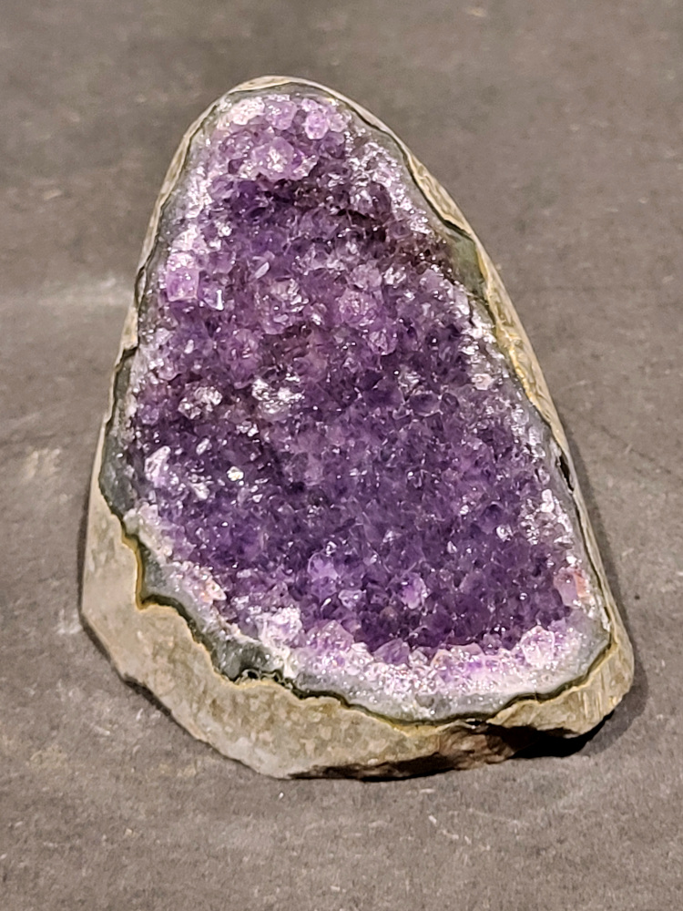 Amethist druzy, 0,3kg, 13,- euro, nr.24

Beschrijving Amethist.
Amethist is een paarse variëteit van kwarts, bekend om zijn kalmerende en spirituele eigenschappen. De kleur varieert van licht lila tot diep violet en wordt veroorzaakt door sporen van ijzer en andere elementen. Amethist wordt al eeuwenlang gewaardeerd, zowel vanwege zijn esthetische schoonheid als zijn vermeende genezende en beschermende krachten. 
Amethist is een kwartskristal, vaak te vinden in geodes (holtes in gesteente) of als afzonderlijke kristallen. 
De kleur varieert van lichtpaars tot diep violet, soms met roze of blauwe tinten. 
De kleurintensiteit kan variëren, waarbij donkerdere amethisten vaak als kwalitatief worden beschouwd. 
Soms vertoont amethist dichroïsme, waarbij je verschillende kleuren kunt zien wanneer je de steen in het licht draait. 

Vindplaatsen:
Amethist wordt gevonden in verschillende delen van de wereld, waaronder Brazilië, Uruguay, Zambia, Madagaskar, Rusland en Canada.
Het wordt vaak gevonden in bergachtige gebieden. 

Gebruik:
Amethist wordt gebruikt in sieraden, decoratieve objecten en als helende steen. 
Het wordt vaak gedragen als hanger, ring of armband, of geplaatst in ruimtes om de energie te zuiveren. 
Amethist wordt ook gebruikt in meditatie en andere spirituele praktijken. 