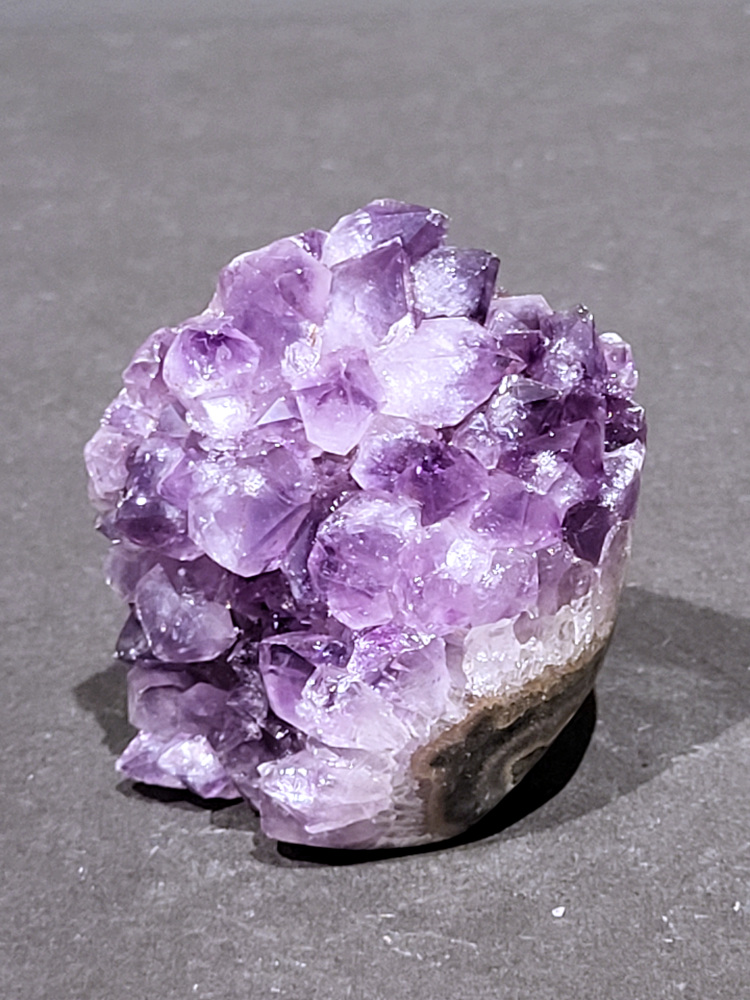 Amethist druzy, 0,3 kg, 13,- euro, nr. 23

Beschrijving Amethist.
Amethist is een paarse variëteit van kwarts, bekend om zijn kalmerende en spirituele eigenschappen. De kleur varieert van licht lila tot diep violet en wordt veroorzaakt door sporen van ijzer en andere elementen. Amethist wordt al eeuwenlang gewaardeerd, zowel vanwege zijn esthetische schoonheid als zijn vermeende genezende en beschermende krachten. 
Amethist is een kwartskristal, vaak te vinden in geodes (holtes in gesteente) of als afzonderlijke kristallen. 
De kleur varieert van lichtpaars tot diep violet, soms met roze of blauwe tinten. 
De kleurintensiteit kan variëren, waarbij donkerdere amethisten vaak als kwalitatief worden beschouwd. 
Soms vertoont amethist dichroïsme, waarbij je verschillende kleuren kunt zien wanneer je de steen in het licht draait. 

Vindplaatsen:
Amethist wordt gevonden in verschillende delen van de wereld, waaronder Brazilië, Uruguay, Zambia, Madagaskar, Rusland en Canada.
Het wordt vaak gevonden in bergachtige gebieden. 

Gebruik:
Amethist wordt gebruikt in sieraden, decoratieve objecten en als helende steen. 
Het wordt vaak gedragen als hanger, ring of armband, of geplaatst in ruimtes om de energie te zuiveren. 
Amethist wordt ook gebruikt in meditatie en andere spirituele praktijken. 