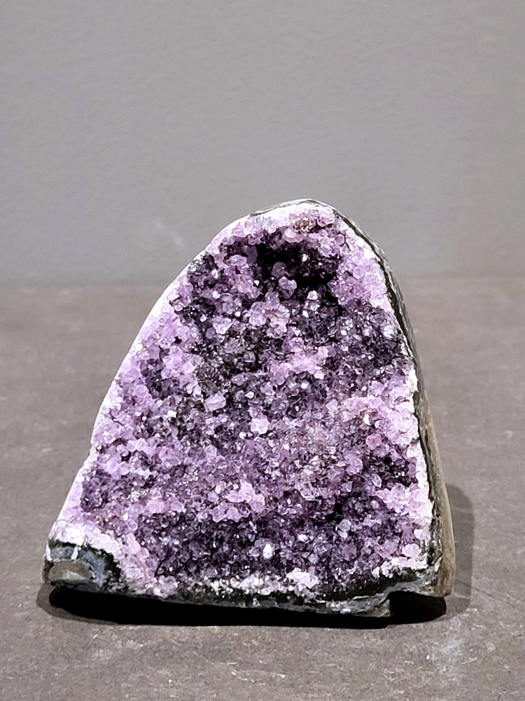 Amethist druzy, 0,4kg, 15,- euro, nr. 58

Beschrijving Amethist.
Amethist is een paarse variëteit van kwarts, bekend om zijn kalmerende en spirituele eigenschappen. De kleur varieert van licht lila tot diep violet en wordt veroorzaakt door sporen van ijzer en andere elementen. Amethist wordt al eeuwenlang gewaardeerd, zowel vanwege zijn esthetische schoonheid als zijn vermeende genezende en beschermende krachten. 
Amethist is een kwartskristal, vaak te vinden in geodes (holtes in gesteente) of als afzonderlijke kristallen. 
De kleur varieert van lichtpaars tot diep violet, soms met roze of blauwe tinten. 
De kleurintensiteit kan variëren, waarbij donkerdere amethisten vaak als kwalitatief worden beschouwd. 
Soms vertoont amethist dichroïsme, waarbij je verschillende kleuren kunt zien wanneer je de steen in het licht draait. 

Vindplaatsen:
Amethist wordt gevonden in verschillende delen van de wereld, waaronder Brazilië, Uruguay, Zambia, Madagaskar, Rusland en Canada.
Het wordt vaak gevonden in bergachtige gebieden. 

Gebruik:
Amethist wordt gebruikt in sieraden, decoratieve objecten en als helende steen. 
Het wordt vaak gedragen als hanger, ring of armband, of geplaatst in ruimtes om de energie te zuiveren. 
Amethist wordt ook gebruikt in meditatie en andere spirituele praktijken. 