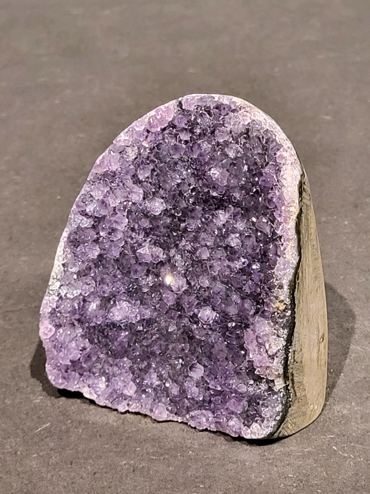 Amethist druzy, 0,4kg, 16,- euro, nr. 56

Beschrijving Amethist.
Amethist is een paarse variëteit van kwarts, bekend om zijn kalmerende en spirituele eigenschappen. De kleur varieert van licht lila tot diep violet en wordt veroorzaakt door sporen van ijzer en andere elementen. Amethist wordt al eeuwenlang gewaardeerd, zowel vanwege zijn esthetische schoonheid als zijn vermeende genezende en beschermende krachten. 
Amethist is een kwartskristal, vaak te vinden in geodes (holtes in gesteente) of als afzonderlijke kristallen. 
De kleur varieert van lichtpaars tot diep violet, soms met roze of blauwe tinten. 
De kleurintensiteit kan variëren, waarbij donkerdere amethisten vaak als kwalitatief worden beschouwd. 
Soms vertoont amethist dichroïsme, waarbij je verschillende kleuren kunt zien wanneer je de steen in het licht draait. 

Vindplaatsen:
Amethist wordt gevonden in verschillende delen van de wereld, waaronder Brazilië, Uruguay, Zambia, Madagaskar, Rusland en Canada.
Het wordt vaak gevonden in bergachtige gebieden. 

Gebruik:
Amethist wordt gebruikt in sieraden, decoratieve objecten en als helende steen. 
Het wordt vaak gedragen als hanger, ring of armband, of geplaatst in ruimtes om de energie te zuiveren. 
Amethist wordt ook gebruikt in meditatie en andere spirituele praktijken. 
