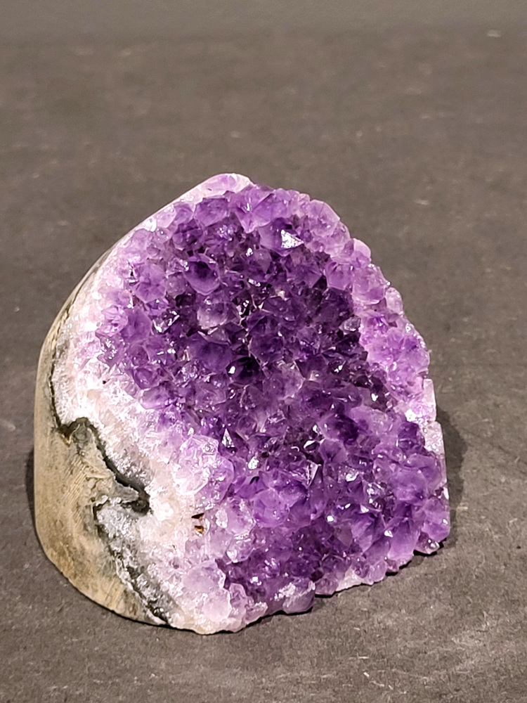 Amethist druzy, 0,4kg, 17,- euro, nr.59

Beschrijving Amethist.
Amethist is een paarse variëteit van kwarts, bekend om zijn kalmerende en spirituele eigenschappen. De kleur varieert van licht lila tot diep violet en wordt veroorzaakt door sporen van ijzer en andere elementen. Amethist wordt al eeuwenlang gewaardeerd, zowel vanwege zijn esthetische schoonheid als zijn vermeende genezende en beschermende krachten. 
Amethist is een kwartskristal, vaak te vinden in geodes (holtes in gesteente) of als afzonderlijke kristallen. 
De kleur varieert van lichtpaars tot diep violet, soms met roze of blauwe tinten. 
De kleurintensiteit kan variëren, waarbij donkerdere amethisten vaak als kwalitatief worden beschouwd. 
Soms vertoont amethist dichroïsme, waarbij je verschillende kleuren kunt zien wanneer je de steen in het licht draait. 

Vindplaatsen:
Amethist wordt gevonden in verschillende delen van de wereld, waaronder Brazilië, Uruguay, Zambia, Madagaskar, Rusland en Canada.
Het wordt vaak gevonden in bergachtige gebieden. 

Gebruik:
Amethist wordt gebruikt in sieraden, decoratieve objecten en als helende steen. 
Het wordt vaak gedragen als hanger, ring of armband, of geplaatst in ruimtes om de energie te zuiveren. 
Amethist wordt ook gebruikt in meditatie en andere spirituele praktijken. 
