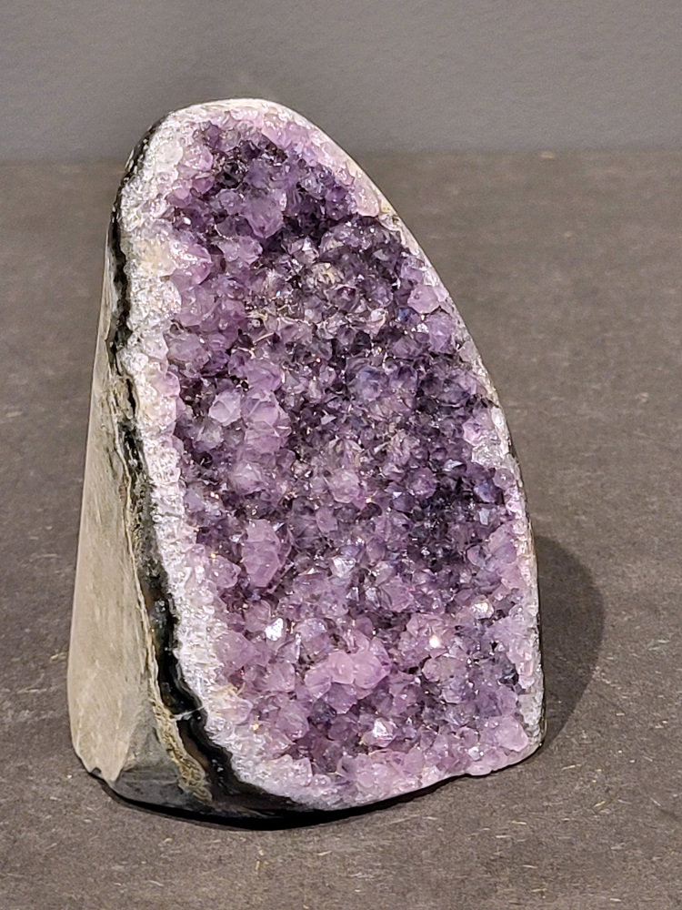 Amethist druzy, 0,6kg, 23,- euro nr.51

Beschrijving Amethist.
Amethist is een paarse variëteit van kwarts, bekend om zijn kalmerende en spirituele eigenschappen. De kleur varieert van licht lila tot diep violet en wordt veroorzaakt door sporen van ijzer en andere elementen. Amethist wordt al eeuwenlang gewaardeerd, zowel vanwege zijn esthetische schoonheid als zijn vermeende genezende en beschermende krachten. 
Amethist is een kwartskristal, vaak te vinden in geodes (holtes in gesteente) of als afzonderlijke kristallen. 
De kleur varieert van lichtpaars tot diep violet, soms met roze of blauwe tinten. 
De kleurintensiteit kan variëren, waarbij donkerdere amethisten vaak als kwalitatief worden beschouwd. 
Soms vertoont amethist dichroïsme, waarbij je verschillende kleuren kunt zien wanneer je de steen in het licht draait. 

Vindplaatsen:
Amethist wordt gevonden in verschillende delen van de wereld, waaronder Brazilië, Uruguay, Zambia, Madagaskar, Rusland en Canada.
Het wordt vaak gevonden in bergachtige gebieden. 

Gebruik:
Amethist wordt gebruikt in sieraden, decoratieve objecten en als helende steen. 
Het wordt vaak gedragen als hanger, ring of armband, of geplaatst in ruimtes om de energie te zuiveren. 
Amethist wordt ook gebruikt in meditatie en andere spirituele praktijken. 