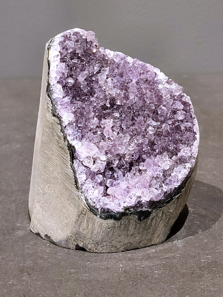 Amethist druzy, 0,6kg, 23,- euro, nr.50

Beschrijving Amethist.
Amethist is een paarse variëteit van kwarts, bekend om zijn kalmerende en spirituele eigenschappen. De kleur varieert van licht lila tot diep violet en wordt veroorzaakt door sporen van ijzer en andere elementen. Amethist wordt al eeuwenlang gewaardeerd, zowel vanwege zijn esthetische schoonheid als zijn vermeende genezende en beschermende krachten. 
Amethist is een kwartskristal, vaak te vinden in geodes (holtes in gesteente) of als afzonderlijke kristallen. 
De kleur varieert van lichtpaars tot diep violet, soms met roze of blauwe tinten. 
De kleurintensiteit kan variëren, waarbij donkerdere amethisten vaak als kwalitatief worden beschouwd. 
Soms vertoont amethist dichroïsme, waarbij je verschillende kleuren kunt zien wanneer je de steen in het licht draait. 

Vindplaatsen:
Amethist wordt gevonden in verschillende delen van de wereld, waaronder Brazilië, Uruguay, Zambia, Madagaskar, Rusland en Canada.
Het wordt vaak gevonden in bergachtige gebieden. 

Gebruik:
Amethist wordt gebruikt in sieraden, decoratieve objecten en als helende steen. 
Het wordt vaak gedragen als hanger, ring of armband, of geplaatst in ruimtes om de energie te zuiveren. 
Amethist wordt ook gebruikt in meditatie en andere spirituele praktijken. 