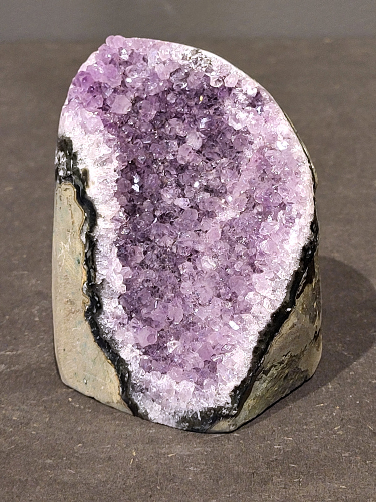 Amethist druzy, 0,6kg, 23,- euro, nr. 60

Beschrijving Amethist.
Amethist is een paarse variëteit van kwarts, bekend om zijn kalmerende en spirituele eigenschappen. De kleur varieert van licht lila tot diep violet en wordt veroorzaakt door sporen van ijzer en andere elementen. Amethist wordt al eeuwenlang gewaardeerd, zowel vanwege zijn esthetische schoonheid als zijn vermeende genezende en beschermende krachten. 
Amethist is een kwartskristal, vaak te vinden in geodes (holtes in gesteente) of als afzonderlijke kristallen. 
De kleur varieert van lichtpaars tot diep violet, soms met roze of blauwe tinten. 
De kleurintensiteit kan variëren, waarbij donkerdere amethisten vaak als kwalitatief worden beschouwd. 
Soms vertoont amethist dichroïsme, waarbij je verschillende kleuren kunt zien wanneer je de steen in het licht draait. 

Vindplaatsen:
Amethist wordt gevonden in verschillende delen van de wereld, waaronder Brazilië, Uruguay, Zambia, Madagaskar, Rusland en Canada.
Het wordt vaak gevonden in bergachtige gebieden. 

Gebruik:
Amethist wordt gebruikt in sieraden, decoratieve objecten en als helende steen. 
Het wordt vaak gedragen als hanger, ring of armband, of geplaatst in ruimtes om de energie te zuiveren. 
Amethist wordt ook gebruikt in meditatie en andere spirituele praktijken. 