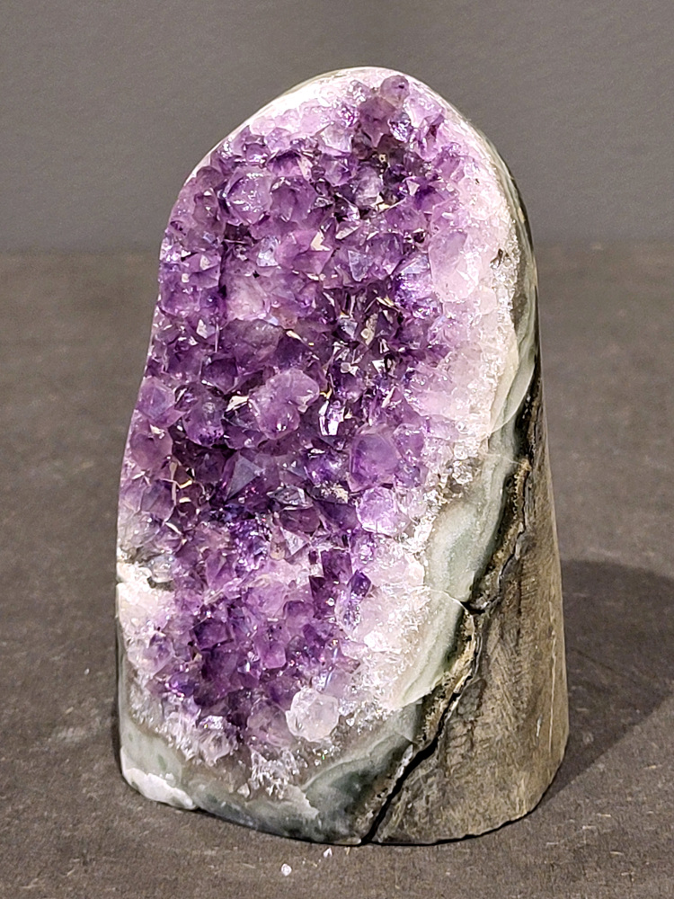 Amethist druzy, 0,7kg, 27,- euro, nr.27

Beschrijving Amethist.
Amethist is een paarse variëteit van kwarts, bekend om zijn kalmerende en spirituele eigenschappen. De kleur varieert van licht lila tot diep violet en wordt veroorzaakt door sporen van ijzer en andere elementen. Amethist wordt al eeuwenlang gewaardeerd, zowel vanwege zijn esthetische schoonheid als zijn vermeende genezende en beschermende krachten. 
Amethist is een kwartskristal, vaak te vinden in geodes (holtes in gesteente) of als afzonderlijke kristallen. 
De kleur varieert van lichtpaars tot diep violet, soms met roze of blauwe tinten. 
De kleurintensiteit kan variëren, waarbij donkerdere amethisten vaak als kwalitatief worden beschouwd. 
Soms vertoont amethist dichroïsme, waarbij je verschillende kleuren kunt zien wanneer je de steen in het licht draait. 

Vindplaatsen:
Amethist wordt gevonden in verschillende delen van de wereld, waaronder Brazilië, Uruguay, Zambia, Madagaskar, Rusland en Canada.
Het wordt vaak gevonden in bergachtige gebieden. 

Gebruik:
Amethist wordt gebruikt in sieraden, decoratieve objecten en als helende steen. 
Het wordt vaak gedragen als hanger, ring of armband, of geplaatst in ruimtes om de energie te zuiveren. 
Amethist wordt ook gebruikt in meditatie en andere spirituele praktijken. 