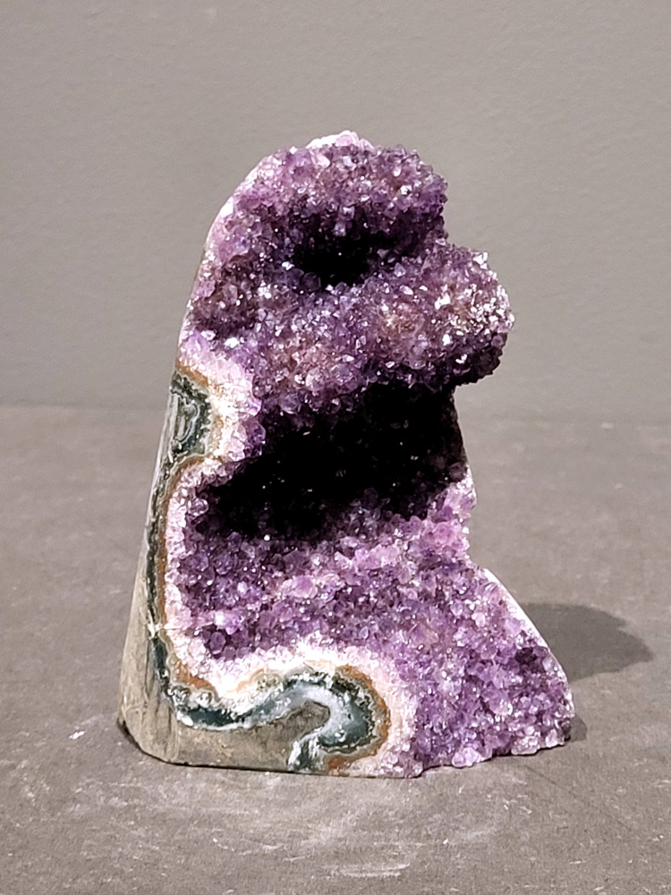 Amethist druzy, 0,7kg, 27,- euro, nr.48

Beschrijving Amethist.
Amethist is een paarse variëteit van kwarts, bekend om zijn kalmerende en spirituele eigenschappen. De kleur varieert van licht lila tot diep violet en wordt veroorzaakt door sporen van ijzer en andere elementen. Amethist wordt al eeuwenlang gewaardeerd, zowel vanwege zijn esthetische schoonheid als zijn vermeende genezende en beschermende krachten. 
Amethist is een kwartskristal, vaak te vinden in geodes (holtes in gesteente) of als afzonderlijke kristallen. 
De kleur varieert van lichtpaars tot diep violet, soms met roze of blauwe tinten. 
De kleurintensiteit kan variëren, waarbij donkerdere amethisten vaak als kwalitatief worden beschouwd. 
Soms vertoont amethist dichroïsme, waarbij je verschillende kleuren kunt zien wanneer je de steen in het licht draait. 

Vindplaatsen:
Amethist wordt gevonden in verschillende delen van de wereld, waaronder Brazilië, Uruguay, Zambia, Madagaskar, Rusland en Canada.
Het wordt vaak gevonden in bergachtige gebieden. 

Gebruik:
Amethist wordt gebruikt in sieraden, decoratieve objecten en als helende steen. 
Het wordt vaak gedragen als hanger, ring of armband, of geplaatst in ruimtes om de energie te zuiveren. 
Amethist wordt ook gebruikt in meditatie en andere spirituele praktijken. 
