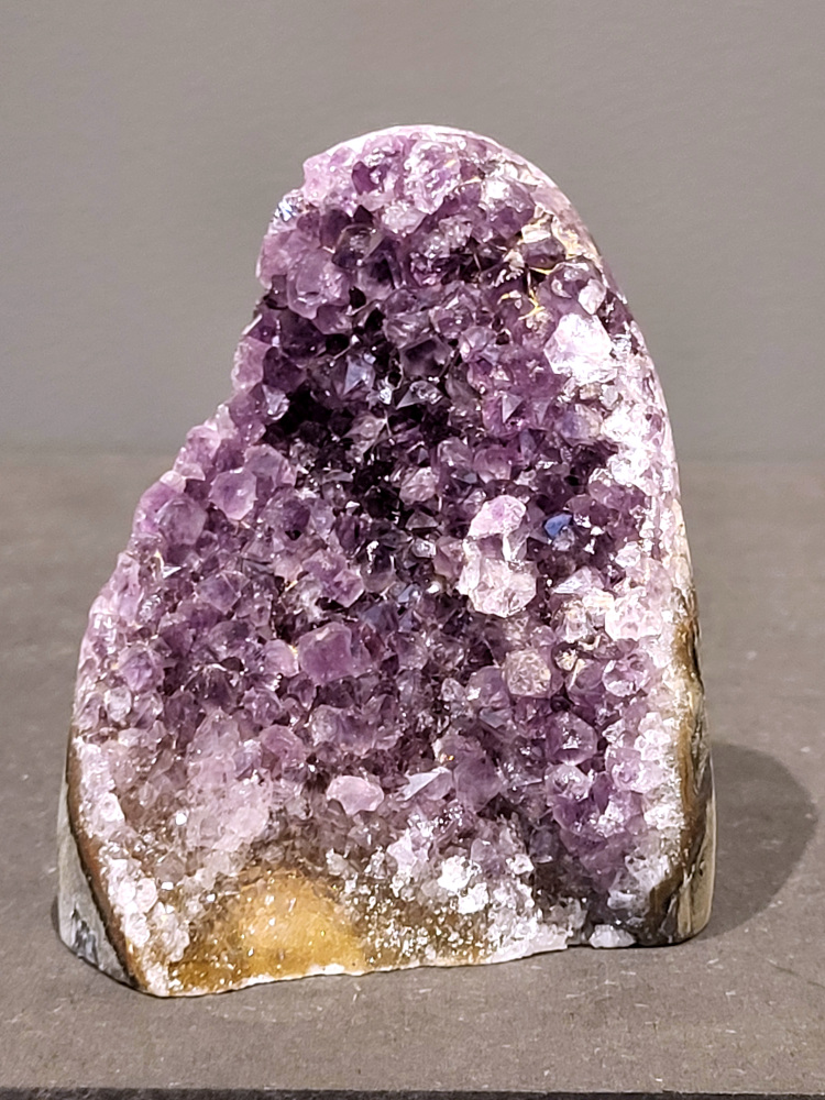 Amethist druzy, 0,8kg, 33,- euro, nr. 46

Beschrijving Amethist.
Amethist is een paarse variëteit van kwarts, bekend om zijn kalmerende en spirituele eigenschappen. De kleur varieert van licht lila tot diep violet en wordt veroorzaakt door sporen van ijzer en andere elementen. Amethist wordt al eeuwenlang gewaardeerd, zowel vanwege zijn esthetische schoonheid als zijn vermeende genezende en beschermende krachten. 
Amethist is een kwartskristal, vaak te vinden in geodes (holtes in gesteente) of als afzonderlijke kristallen. 
De kleur varieert van lichtpaars tot diep violet, soms met roze of blauwe tinten. 
De kleurintensiteit kan variëren, waarbij donkerdere amethisten vaak als kwalitatief worden beschouwd. 
Soms vertoont amethist dichroïsme, waarbij je verschillende kleuren kunt zien wanneer je de steen in het licht draait. 

Vindplaatsen:
Amethist wordt gevonden in verschillende delen van de wereld, waaronder Brazilië, Uruguay, Zambia, Madagaskar, Rusland en Canada.
Het wordt vaak gevonden in bergachtige gebieden. 

Gebruik:
Amethist wordt gebruikt in sieraden, decoratieve objecten en als helende steen. 
Het wordt vaak gedragen als hanger, ring of armband, of geplaatst in ruimtes om de energie te zuiveren. 
Amethist wordt ook gebruikt in meditatie en andere spirituele praktijken. 