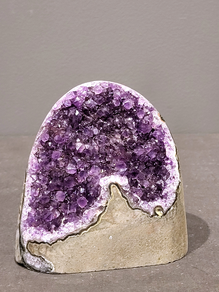 Amethist druzy, 0,9kg, 35,- euro, nr.38

Beschrijving Amethist.
Amethist is een paarse variëteit van kwarts, bekend om zijn kalmerende en spirituele eigenschappen. De kleur varieert van licht lila tot diep violet en wordt veroorzaakt door sporen van ijzer en andere elementen. Amethist wordt al eeuwenlang gewaardeerd, zowel vanwege zijn esthetische schoonheid als zijn vermeende genezende en beschermende krachten. 
Amethist is een kwartskristal, vaak te vinden in geodes (holtes in gesteente) of als afzonderlijke kristallen. 
De kleur varieert van lichtpaars tot diep violet, soms met roze of blauwe tinten. 
De kleurintensiteit kan variëren, waarbij donkerdere amethisten vaak als kwalitatief worden beschouwd. 
Soms vertoont amethist dichroïsme, waarbij je verschillende kleuren kunt zien wanneer je de steen in het licht draait. 

Vindplaatsen:
Amethist wordt gevonden in verschillende delen van de wereld, waaronder Brazilië, Uruguay, Zambia, Madagaskar, Rusland en Canada.
Het wordt vaak gevonden in bergachtige gebieden. 

Gebruik:
Amethist wordt gebruikt in sieraden, decoratieve objecten en als helende steen. 
Het wordt vaak gedragen als hanger, ring of armband, of geplaatst in ruimtes om de energie te zuiveren. 
Amethist wordt ook gebruikt in meditatie en andere spirituele praktijken. 