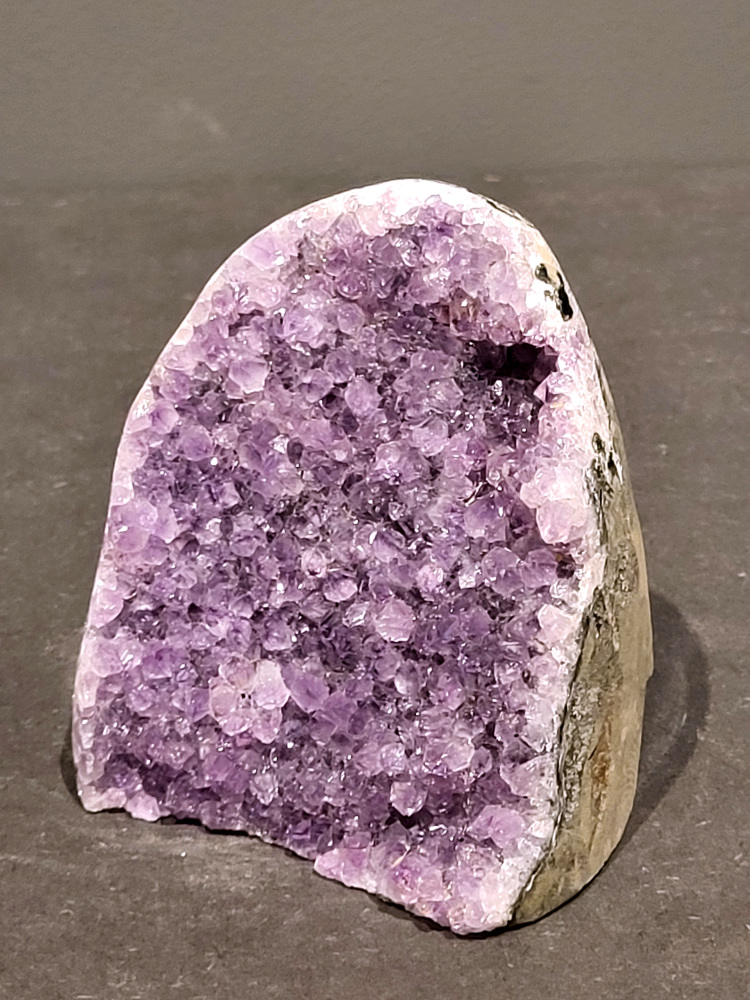 Amethist druzy, 0,9kg, 35,- euro, nr.44

Beschrijving Amethist.
Amethist is een paarse variëteit van kwarts, bekend om zijn kalmerende en spirituele eigenschappen. De kleur varieert van licht lila tot diep violet en wordt veroorzaakt door sporen van ijzer en andere elementen. Amethist wordt al eeuwenlang gewaardeerd, zowel vanwege zijn esthetische schoonheid als zijn vermeende genezende en beschermende krachten. 
Amethist is een kwartskristal, vaak te vinden in geodes (holtes in gesteente) of als afzonderlijke kristallen. 
De kleur varieert van lichtpaars tot diep violet, soms met roze of blauwe tinten. 
De kleurintensiteit kan variëren, waarbij donkerdere amethisten vaak als kwalitatief worden beschouwd. 
Soms vertoont amethist dichroïsme, waarbij je verschillende kleuren kunt zien wanneer je de steen in het licht draait. 

Vindplaatsen:
Amethist wordt gevonden in verschillende delen van de wereld, waaronder Brazilië, Uruguay, Zambia, Madagaskar, Rusland en Canada.
Het wordt vaak gevonden in bergachtige gebieden. 

Gebruik:
Amethist wordt gebruikt in sieraden, decoratieve objecten en als helende steen. 
Het wordt vaak gedragen als hanger, ring of armband, of geplaatst in ruimtes om de energie te zuiveren. 
Amethist wordt ook gebruikt in meditatie en andere spirituele praktijken. 