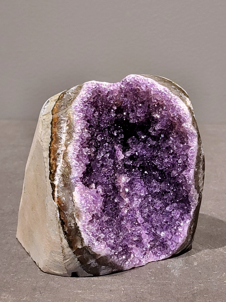 Amethist druzy, 0,9kg, 36,- euro, nr. 37

Beschrijving Amethist.
Amethist is een paarse variëteit van kwarts, bekend om zijn kalmerende en spirituele eigenschappen. De kleur varieert van licht lila tot diep violet en wordt veroorzaakt door sporen van ijzer en andere elementen. Amethist wordt al eeuwenlang gewaardeerd, zowel vanwege zijn esthetische schoonheid als zijn vermeende genezende en beschermende krachten. 
Amethist is een kwartskristal, vaak te vinden in geodes (holtes in gesteente) of als afzonderlijke kristallen. 
De kleur varieert van lichtpaars tot diep violet, soms met roze of blauwe tinten. 
De kleurintensiteit kan variëren, waarbij donkerdere amethisten vaak als kwalitatief worden beschouwd. 
Soms vertoont amethist dichroïsme, waarbij je verschillende kleuren kunt zien wanneer je de steen in het licht draait. 

Vindplaatsen:
Amethist wordt gevonden in verschillende delen van de wereld, waaronder Brazilië, Uruguay, Zambia, Madagaskar, Rusland en Canada.
Het wordt vaak gevonden in bergachtige gebieden. 

Gebruik:
Amethist wordt gebruikt in sieraden, decoratieve objecten en als helende steen. 
Het wordt vaak gedragen als hanger, ring of armband, of geplaatst in ruimtes om de energie te zuiveren. 
Amethist wordt ook gebruikt in meditatie en andere spirituele praktijken. 