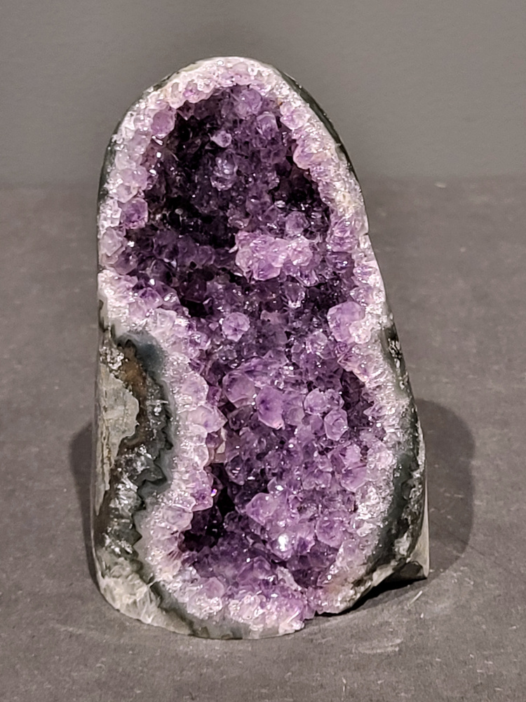Amethist druzy, 1kg, 39,- euro, nr. 28

Beschrijving Amethist.
Amethist is een paarse variëteit van kwarts, bekend om zijn kalmerende en spirituele eigenschappen. De kleur varieert van licht lila tot diep violet en wordt veroorzaakt door sporen van ijzer en andere elementen. Amethist wordt al eeuwenlang gewaardeerd, zowel vanwege zijn esthetische schoonheid als zijn vermeende genezende en beschermende krachten. 
Amethist is een kwartskristal, vaak te vinden in geodes (holtes in gesteente) of als afzonderlijke kristallen. 
De kleur varieert van lichtpaars tot diep violet, soms met roze of blauwe tinten. 
De kleurintensiteit kan variëren, waarbij donkerdere amethisten vaak als kwalitatief worden beschouwd. 
Soms vertoont amethist dichroïsme, waarbij je verschillende kleuren kunt zien wanneer je de steen in het licht draait. 

Vindplaatsen:
Amethist wordt gevonden in verschillende delen van de wereld, waaronder Brazilië, Uruguay, Zambia, Madagaskar, Rusland en Canada.
Het wordt vaak gevonden in bergachtige gebieden. 

Gebruik:
Amethist wordt gebruikt in sieraden, decoratieve objecten en als helende steen. 
Het wordt vaak gedragen als hanger, ring of armband, of geplaatst in ruimtes om de energie te zuiveren. 
Amethist wordt ook gebruikt in meditatie en andere spirituele praktijken. 