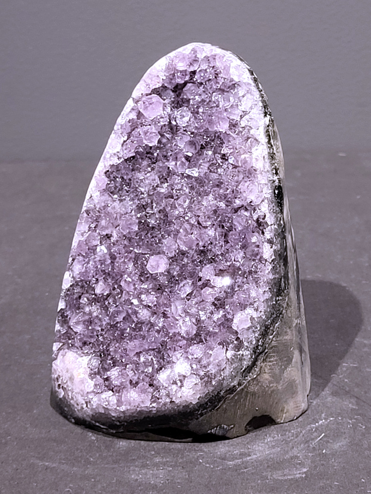 Amethist druzy, 1kg, 41,- euro, nr. 41

Beschrijving Amethist.
Amethist is een paarse variëteit van kwarts, bekend om zijn kalmerende en spirituele eigenschappen. De kleur varieert van licht lila tot diep violet en wordt veroorzaakt door sporen van ijzer en andere elementen. Amethist wordt al eeuwenlang gewaardeerd, zowel vanwege zijn esthetische schoonheid als zijn vermeende genezende en beschermende krachten. 
Amethist is een kwartskristal, vaak te vinden in geodes (holtes in gesteente) of als afzonderlijke kristallen. 
De kleur varieert van lichtpaars tot diep violet, soms met roze of blauwe tinten. 
De kleurintensiteit kan variëren, waarbij donkerdere amethisten vaak als kwalitatief worden beschouwd. 
Soms vertoont amethist dichroïsme, waarbij je verschillende kleuren kunt zien wanneer je de steen in het licht draait. 

Vindplaatsen:
Amethist wordt gevonden in verschillende delen van de wereld, waaronder Brazilië, Uruguay, Zambia, Madagaskar, Rusland en Canada.
Het wordt vaak gevonden in bergachtige gebieden. 

Gebruik:
Amethist wordt gebruikt in sieraden, decoratieve objecten en als helende steen. 
Het wordt vaak gedragen als hanger, ring of armband, of geplaatst in ruimtes om de energie te zuiveren. 
Amethist wordt ook gebruikt in meditatie en andere spirituele praktijken. 