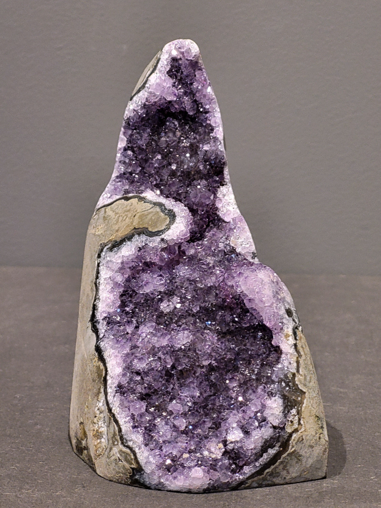 Amethist druzy, 1kg, 41,- euro, nr. 29

Beschrijving Amethist.
Amethist is een paarse variëteit van kwarts, bekend om zijn kalmerende en spirituele eigenschappen. De kleur varieert van licht lila tot diep violet en wordt veroorzaakt door sporen van ijzer en andere elementen. Amethist wordt al eeuwenlang gewaardeerd, zowel vanwege zijn esthetische schoonheid als zijn vermeende genezende en beschermende krachten. 
Amethist is een kwartskristal, vaak te vinden in geodes (holtes in gesteente) of als afzonderlijke kristallen. 
De kleur varieert van lichtpaars tot diep violet, soms met roze of blauwe tinten. 
De kleurintensiteit kan variëren, waarbij donkerdere amethisten vaak als kwalitatief worden beschouwd. 
Soms vertoont amethist dichroïsme, waarbij je verschillende kleuren kunt zien wanneer je de steen in het licht draait. 

Vindplaatsen:
Amethist wordt gevonden in verschillende delen van de wereld, waaronder Brazilië, Uruguay, Zambia, Madagaskar, Rusland en Canada.
Het wordt vaak gevonden in bergachtige gebieden. 

Gebruik:
Amethist wordt gebruikt in sieraden, decoratieve objecten en als helende steen. 
Het wordt vaak gedragen als hanger, ring of armband, of geplaatst in ruimtes om de energie te zuiveren. 
Amethist wordt ook gebruikt in meditatie en andere spirituele praktijken. 