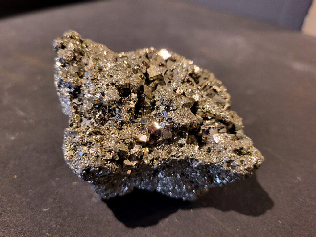 Pyriet, 0,3kg, 12,- euro, nr. 1

Pyriet, ook wel bekend als klatergoud. Het is een mineraal van ijzer en zwavel met een goudgele, metaalachtige glans, wat het soms doet lijken op goud. De naam komt van het Griekse woord voor 'vuur' ,
 omdat het vonken geeft als je het ergens tegenaan slaat. Het wordt industrieel gebruikt voor de productie van zwavelzuur en als decoratieve steen, terwijl het in de oudheid diende als vuursteen. 
Kenmerken 
Uiterlijk: Goudgeel met een metaalachtige glans. De kristallen zijn vaak kubusvormig, maar kunnen ook andere vormen hebben.
Naam: Afgeleid van het Griekse woord voor 'vuur', vanwege het vonkend effect bij impact.
Bijnaam: Ook wel "klatergoud" of "goud der dwazen" genoemd vanwege de gelijkenis met echt goud. 
Toepassingen en gebruik 
Industrie: Het is een belangrijke bron voor de productie van zwavelzuur, dat onder andere wordt gebruikt in kunstmest en olieraffinage.
Geschiedenis: In de oudheid werd het gebruikt als vuursteen om vuur te maken.
Decoratie en sieraden: Vanwege zijn goudachtige uiterlijk wordt het veel gebruikt in sieraden en decoratieve objecten.
Wetenschap: Het dient als indicator voor geologische processen en wordt gebruikt in mineralogisch onderzoek. 
Onderscheid met goud 
Textuur: Ruwe pyrietkristallen hebben scherpere randen dan ruw goud.
Kleur: Pyriet heeft vaker een koperachtige tint, terwijl echt goud een helderder, geelgouden kleur heeft.
Hardheid: Pyriet is harder dan goud (hardheid van 6-6,5 versus 2,5).
Dichtheid: Pyriet is lichter in gewicht dan goud.