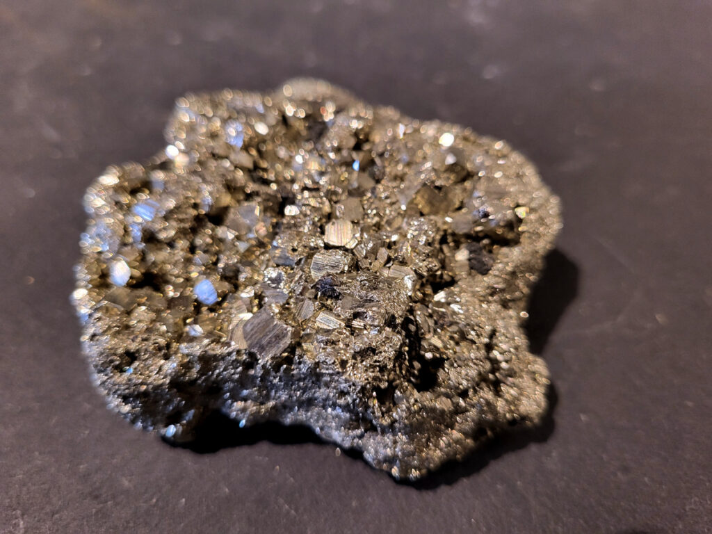 Pyriet, 0,4kg, 12,50 euro, nr. 2

Pyriet, ook wel bekend als klatergoud. Het is een mineraal van ijzer en zwavel met een goudgele, metaalachtige glans, wat het soms doet lijken op goud. De naam komt van het Griekse woord voor 'vuur' ,
 omdat het vonken geeft als je het ergens tegenaan slaat. Het wordt industrieel gebruikt voor de productie van zwavelzuur en als decoratieve steen, terwijl het in de oudheid diende als vuursteen. 
Kenmerken 
Uiterlijk: Goudgeel met een metaalachtige glans. De kristallen zijn vaak kubusvormig, maar kunnen ook andere vormen hebben.
Naam: Afgeleid van het Griekse woord voor 'vuur', vanwege het vonkend effect bij impact.
Bijnaam: Ook wel "klatergoud" of "goud der dwazen" genoemd vanwege de gelijkenis met echt goud. 
Toepassingen en gebruik 
Industrie: Het is een belangrijke bron voor de productie van zwavelzuur, dat onder andere wordt gebruikt in kunstmest en olieraffinage.
Geschiedenis: In de oudheid werd het gebruikt als vuursteen om vuur te maken.
Decoratie en sieraden: Vanwege zijn goudachtige uiterlijk wordt het veel gebruikt in sieraden en decoratieve objecten.
Wetenschap: Het dient als indicator voor geologische processen en wordt gebruikt in mineralogisch onderzoek. 
Onderscheid met goud 
Textuur: Ruwe pyrietkristallen hebben scherpere randen dan ruw goud.
Kleur: Pyriet heeft vaker een koperachtige tint, terwijl echt goud een helderder, geelgouden kleur heeft.
Hardheid: Pyriet is harder dan goud (hardheid van 6-6,5 versus 2,5).
Dichtheid: Pyriet is lichter in gewicht dan goud.