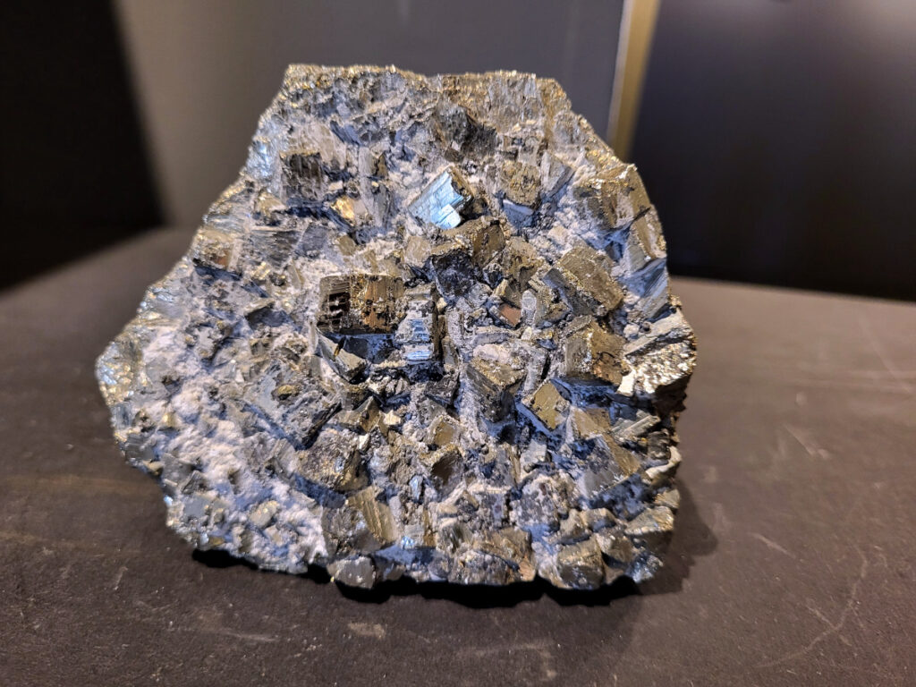 Pyriet, 1,1kg, 40,- euro, nr 4

Pyriet, ook wel bekend als klatergoud. Het is een mineraal van ijzer en zwavel met een goudgele, metaalachtige glans, wat het soms doet lijken op goud. De naam komt van het Griekse woord voor 'vuur' ,
 omdat het vonken geeft als je het ergens tegenaan slaat. Het wordt industrieel gebruikt voor de productie van zwavelzuur en als decoratieve steen, terwijl het in de oudheid diende als vuursteen. 
Kenmerken 
Uiterlijk: Goudgeel met een metaalachtige glans. De kristallen zijn vaak kubusvormig, maar kunnen ook andere vormen hebben.
Naam: Afgeleid van het Griekse woord voor 'vuur', vanwege het vonkend effect bij impact.
Bijnaam: Ook wel "klatergoud" of "goud der dwazen" genoemd vanwege de gelijkenis met echt goud. 
Toepassingen en gebruik 
Industrie: Het is een belangrijke bron voor de productie van zwavelzuur, dat onder andere wordt gebruikt in kunstmest en olieraffinage.
Geschiedenis: In de oudheid werd het gebruikt als vuursteen om vuur te maken.
Decoratie en sieraden: Vanwege zijn goudachtige uiterlijk wordt het veel gebruikt in sieraden en decoratieve objecten.
Wetenschap: Het dient als indicator voor geologische processen en wordt gebruikt in mineralogisch onderzoek. 
Onderscheid met goud 
Textuur: Ruwe pyrietkristallen hebben scherpere randen dan ruw goud.
Kleur: Pyriet heeft vaker een koperachtige tint, terwijl echt goud een helderder, geelgouden kleur heeft.
Hardheid: Pyriet is harder dan goud (hardheid van 6-6,5 versus 2,5).
Dichtheid: Pyriet is lichter in gewicht dan goud.