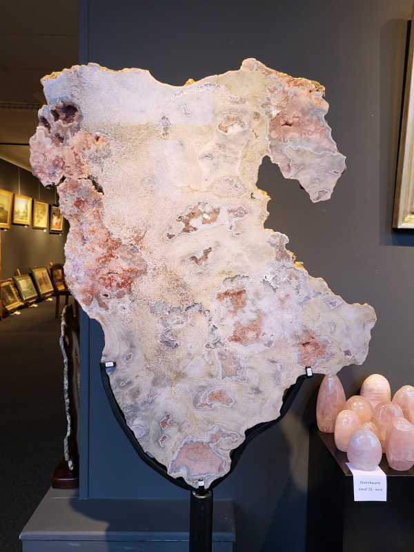 Roze Amethist, Chalcedoon, 33kg, 170cm hoog, 90cm doorsnee, 1150,- euro, nr. 24

Chalcedoon, ook wel genoemd Roze Amethist

Chalcedoon is een edelsteen die behoort tot de kwartsfamilie en bekend staat om zijn zachte, wasachtige glans en diverse kleuren. Het is een microkristallijne vorm van kwarts, vaak in wit, grijs, blauw, geel, bruin of rood. Chalcedoon wordt gewaardeerd om zijn spirituele eigenschappen, zoals het bevorderen van communicatie, evenwicht en creativiteit. 
Kenmerken en soorten:
Chalcedoon is een cryptokristal gelijnde  kwarts, wat betekent dat de kristallen zo klein zijn dat ze met het blote oog niet te zien zijn. 
Het heeft een hardheid van 6,5-7 op de schaal van Mohs. 
Bekende variëteiten van chalcedoon zijn chrysopraas (appelgroen), carneool (roze tot rood) en sarder (bruin). 
Blauwe chalcedoon, met name Blue Lace Agate, staat bekend om zijn kalmerende werking en wordt geassocieerd met de keelchakra. 
Spirituele eigenschappen en werking:
Chalcedoon wordt gezien als de steen van communicatie en wordt vaak de "redenaarssteen" genoemd. 
Het bevordert helderheid van geest, zelfvertrouwen en moed om gevoelens te uiten. 
Chalcedoon kan helpen bij het loslaten van onderdrukte emoties en het vinden van innerlijke rust. 
Het wordt ook in verband gebracht met creativiteit en het vermogen om ideeën om te zetten in daden. 
Sommige geloven dat chalcedoon het keelchakra activeert en helpt bij problemen met de keel, stembanden en schildklier. 
Fysieke werking:
Chalcedoon wordt verondersteld reinigende, verkoelende en ontstekingsremmende eigenschappen te hebben.
Het kan helpen bij koorts, verkoudheid, ademhalingsproblemen en het versterken van het immuunsysteem. 
Chalcedoon wordt ook in verband gebracht met een positieve werking op de bloedsomloop, vochtophoping en de productie van insuline.
Overige:
Chalcedoon komt voor in verschillende delen van de wereld, waaronder Brazilië, Madagaskar, India en Uruguay. 
In de oudheid werd chalcedoon al gebruikt voor amuletten, zegels en sieraden.