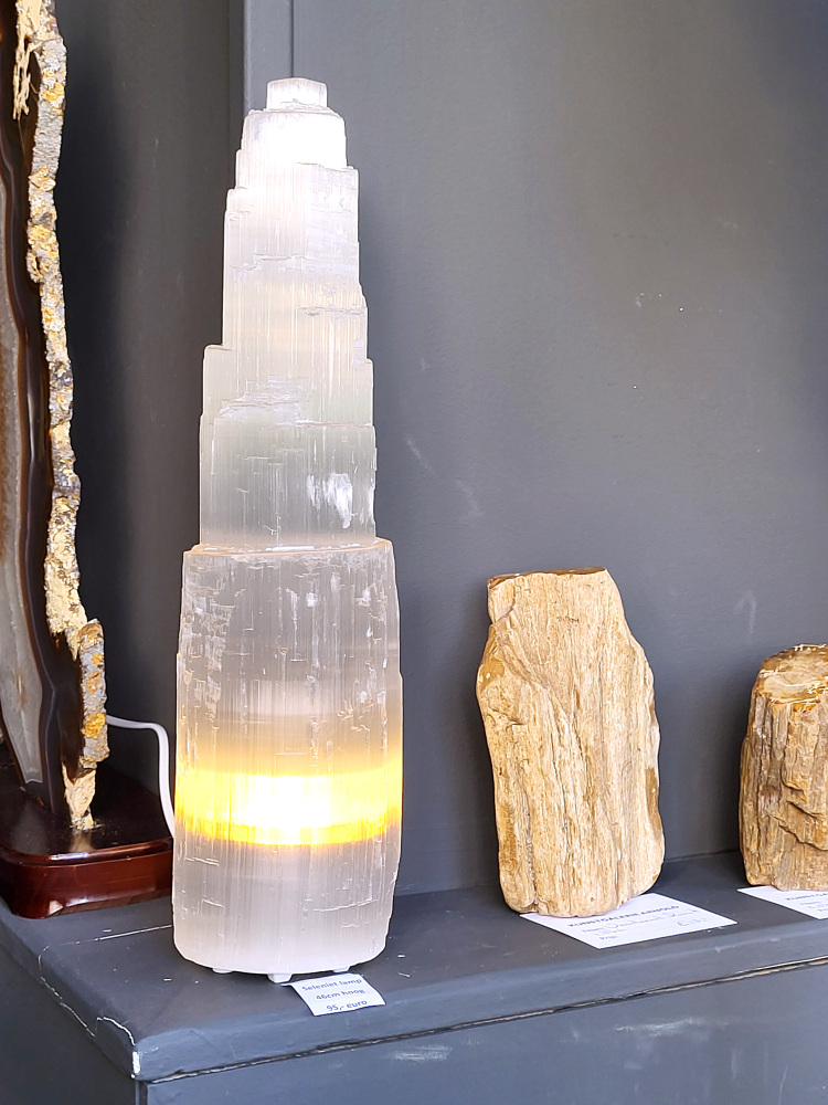 Seleniet lamp, 46cm hoog, XXL formaat, 95,- euro, nr. 51

Seleniet is een kristallijne vorm van gips, ook wel satijnspaat genoemd, bekend om zijn zuiverende en spirituele eigenschappen. Het mineraal is relatief zacht, is te vinden in verschillende kleuren (wit, oranje, geel, groen) en wordt vaak gebruikt bij healing en meditatie. Seleniet wordt spiritueel geassocieerd met rust, heling en het reinigen van energie, en het staat bekend om zijn zelfreinigende en het reinigen van andere stenen. 
Eigenschappen en uiterlijk
Samenstelling: Seleniet is een gehydrateerd calciumsulfaat en een variant van gips.
Hardheid: Met een hardheid van 2 is het een zachte steen.
Vorm: Het komt vaak voor in lange, heldere, tabulaire kristallen met een vezelige structuur.
Kleur: De kleur kan variëren, maar de meest voorkomende kleuren zijn wit, kleurloos, geel, oranje en groen. De witte variant wordt vaak satijnspaat genoemd.
Bijzonderheden: Sommige selenietkristallen kunnen flexibel zijn en enhydrokristallen kunnen kleine water- en gasbelletjes bevatten. 
Spirituele betekenis en gebruik
Reiniging: Seleniet wordt beschouwd als een krachtige zuiveraar die negatieve energie verwijdert en harmonie brengt.
Healing en meditatie: Het wordt vaak gebruikt tijdens meditatie, healing en voor het communiceren met hogere sferen.
Zelfreinigend: Seleniet is een zelfreinigende steen en wordt vaak gebruikt om andere edelstenen energetisch op te laden.
Chakra's: Het is sterk verbonden met de kruin- en derde-oogchakra, wat helpt bij spiritueel bewustzijn en intuïtie.
Spirituele namen: Het wordt ook wel "engelensteen" genoemd vanwege de hoge vibratie die heling en transformatie brengt. 
Verzorging
Vermijd water: Omdat het een gipsvariant is, mag seleniet nooit worden gereinigd met water, aangezien het kan oplossen of beschadigen.
Reinigingsmethodes: Reinig het energetisch met rook van salie of palo santo, of door het op een cluster van amethist of hematiet te plaatsen.
Opladen: Om seleniet op te laden, kan maanlicht of een bergkristal worden gebruikt.