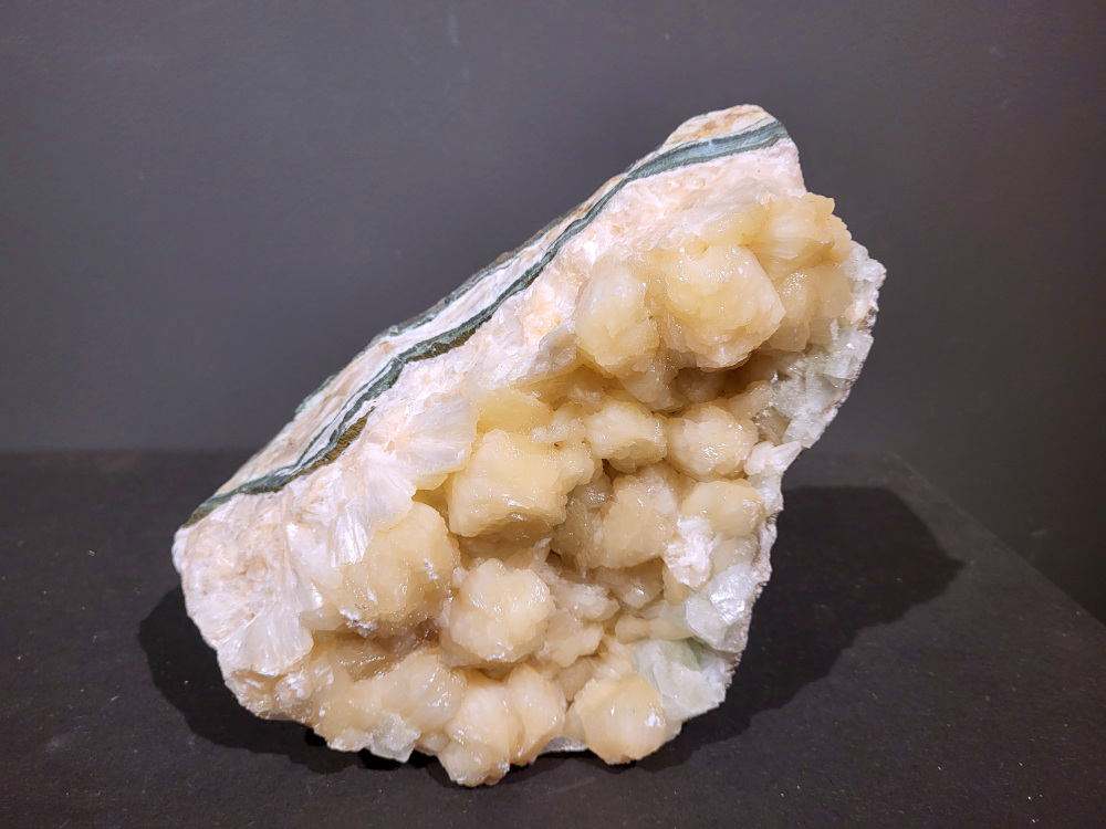 Stilbiet Cluster, 5kg, 95,- euro, nr. 11

Stilbiet (ook wel stilbite genoemd), vaak gevonden samen met apofyliet in Indiase geodes.
Uiterlijk:
Perzik- tot crème-witte kleur,
Glanzende, waaier- of bloemvormige kristalstructuur,
Zachte, zijdeachtige glans (bijna parelmoerachtig),
al die kenmerken passen heel goed bij stilbiet.
De ronde, lichtgrijze korrelige bol bovenop kan een heulandiet- of chalcedoon-vorming zijn die samen met de stilbiet is gegroeid.
Energetische betekenis:
Stilbiet hoort bij het hart en het kruinchakra is een zachte, troostende energie die helpt bij het loslaten van oude patronen en het verbinden met hogere leiding.
Ze ondersteunt intuïtie, dromen en zachtheid in relaties — een heel liefdevolle steen om in huis te hebben, vooral bij healing- of slaapruimtes.