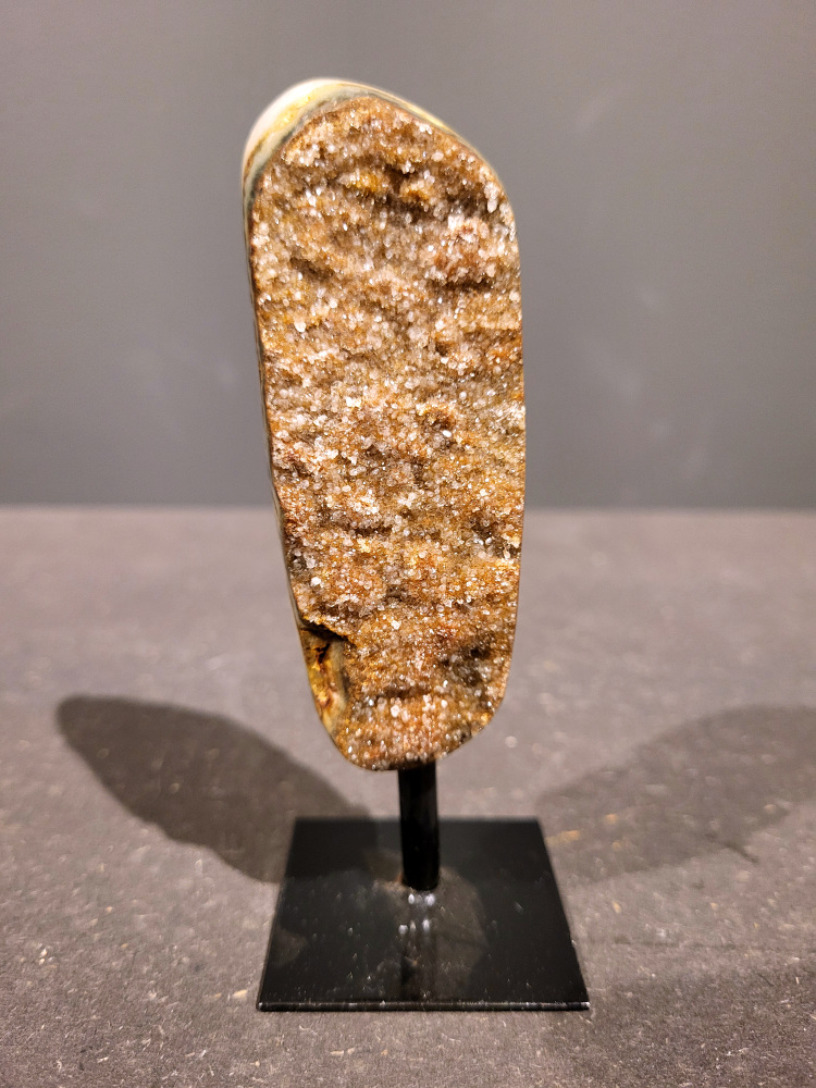 <strong>Agaat op standaard, 0,1kg, 13cm hoog, 7,- euro, nr. 2</strong>

<strong>Beschrijving Agaat.</strong>

Agaat is een veelzijdige edelsteen die bekend staat om zijn prachtige kleurbanden en patronen. Het is een variëteit van het mineraal kwarts, meer specifiek chalcedoon, en wordt vaak gebruikt in sieraden en als decoratieve steen. 
<strong>Algemene kenmerken:</strong>
Agaat is een microkristallijne vorm van kwarts, bestaande uit microscopisch kleine kristallen. 
<strong>Kleuren en patronen:</strong>
Agaat komt voor in vele kleuren, vaak met banden of lagen in verschillende tinten. 
Agaat is een populaire keuze voor het maken van kettingen, armbanden, ringen en andere sieraden vanwege de esthetische aantrekkingskracht en duurzaamheid. 
<strong>Spirituele eigenschappen:</strong>
Agaat wordt vaak geassocieerd met aardende, stabiliserende en beschermende eigenschappen. 
<strong>Helende werking:</strong>
Er wordt aangenomen dat agaat kan helpen bij het verminderen van stress, het bevorderen van emotioneel evenwicht en het versterken van het zelfvertrouwen. 
<strong>Verzorging van agaat:</strong>
Agaat is relatief gemakkelijk te onderhouden. Het kan worden gereinigd met lauw water, de rook van witte salie of palo santo, of door het op een hematiet- of bergkristal-cluster te plaatsen. 

<strong>-	Kunstgalerie-Arnold -</strong>