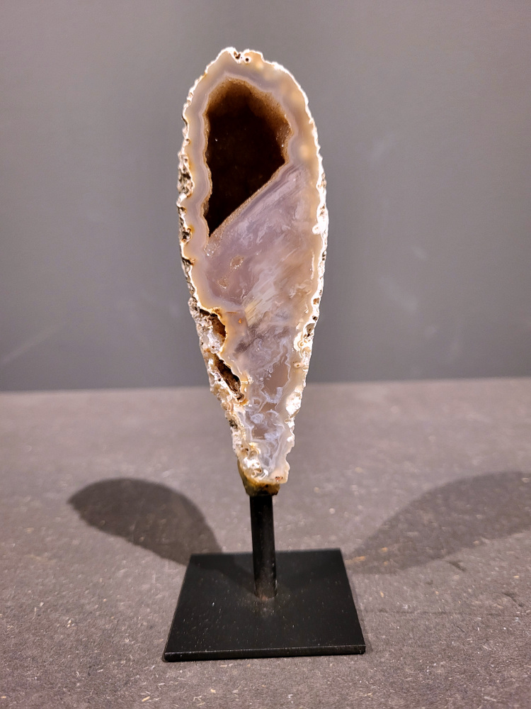 <strong>Agaat op standaard, 0,2kg, 15cm hoog, 10,- euro, nr. 4</strong>

<strong>Beschrijving Agaat.</strong>

Agaat is een veelzijdige edelsteen die bekend staat om zijn prachtige kleurbanden en patronen. Het is een variëteit van het mineraal kwarts, meer specifiek chalcedoon, en wordt vaak gebruikt in sieraden en als decoratieve steen. 
<strong>Algemene kenmerken:</strong>
Agaat is een microkristallijne vorm van kwarts, bestaande uit microscopisch kleine kristallen. 
<strong>Kleuren en patronen:</strong>
Agaat komt voor in vele kleuren, vaak met banden of lagen in verschillende tinten. 
Agaat is een populaire keuze voor het maken van kettingen, armbanden, ringen en andere sieraden vanwege de esthetische aantrekkingskracht en duurzaamheid. 
<strong>Spirituele eigenschappen:</strong>
Agaat wordt vaak geassocieerd met aardende, stabiliserende en beschermende eigenschappen. 
<strong>Helende werking:</strong>
Er wordt aangenomen dat agaat kan helpen bij het verminderen van stress, het bevorderen van emotioneel evenwicht en het versterken van het zelfvertrouwen. 
<strong>Verzorging van agaat:</strong>
Agaat is relatief gemakkelijk te onderhouden. Het kan worden gereinigd met lauw water, de rook van witte salie of palo santo, of door het op een hematiet- of bergkristal-cluster te plaatsen. 

<strong>-	Kunstgalerie-Arnold -</strong>